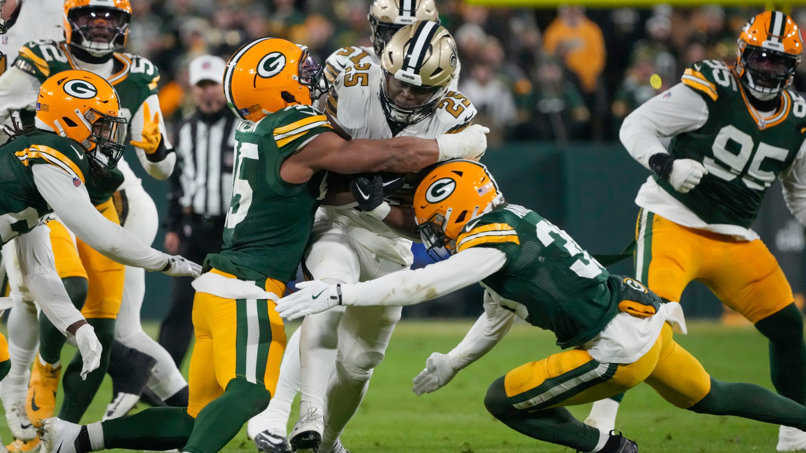 New Orleans Saints running back Kendre Miller (25) is stopped by Green Bay Packers linebacker Eric Wilson and safety Zayne Anderson, right, during the first half of an NFL football game, Monday, Dec. 23, 2024, in Green Bay, Wis. (AP Photo/Morry Gash)