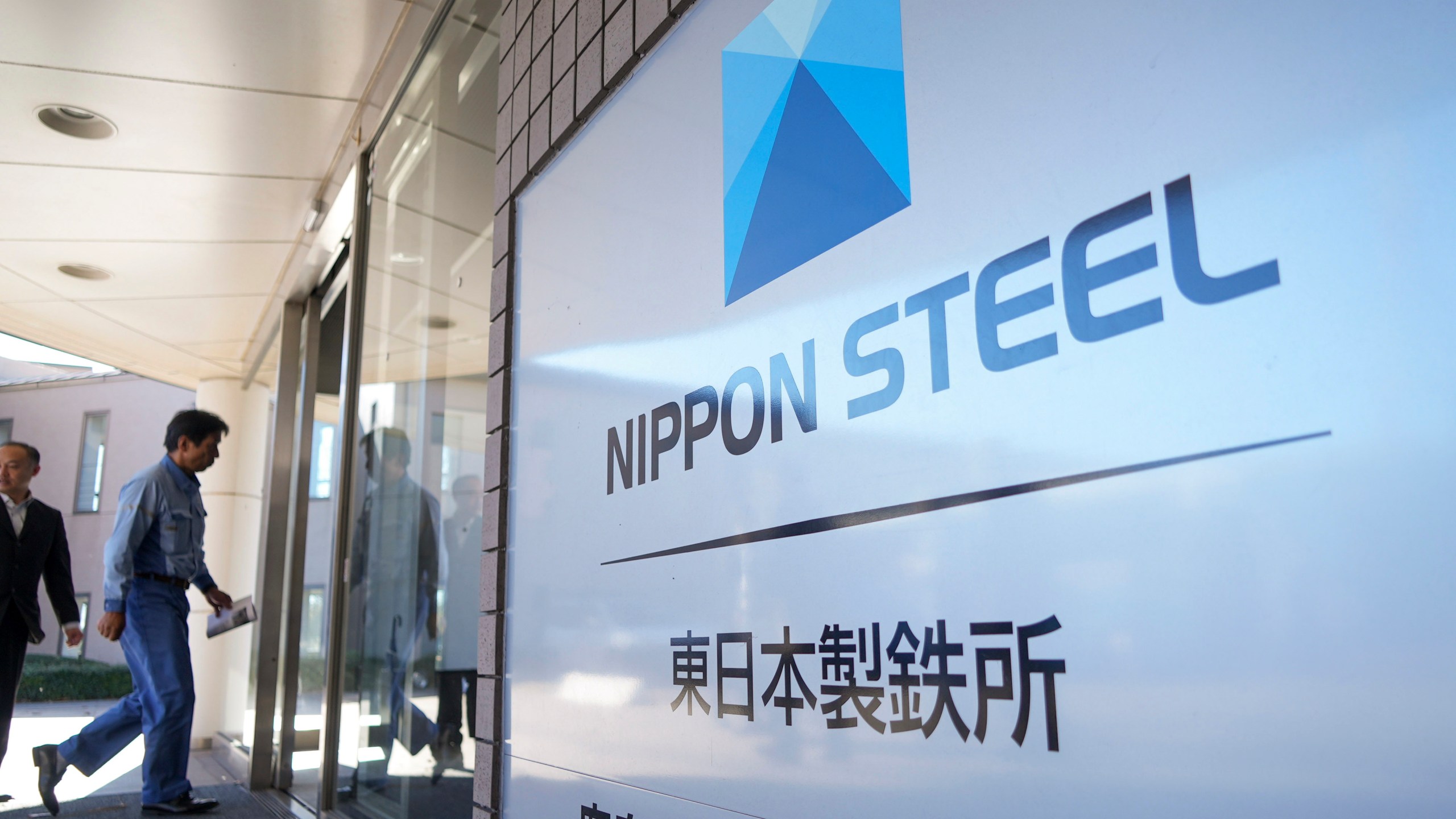 A staff enters doorway next to Nippon Steel logo at the company's Kashima Plant in Kashima, Japan on Friday, Dec. 6, 2024. (AP Photo/Ayaka McGill)