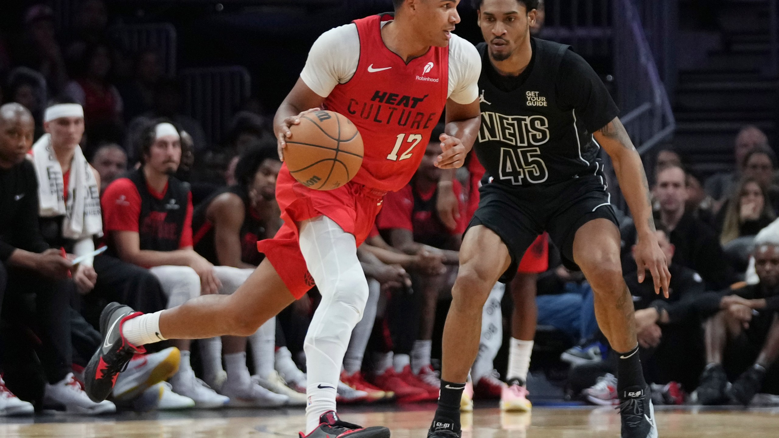 Miami Heat guard Dru Smith (12) dribbles as Brooklyn Nets guard Keon Johnson (45) defends during the first half of an NBA basketball game, Monday, Dec. 23, 2024, in Miami. (AP Photo/Lynne Sladky)