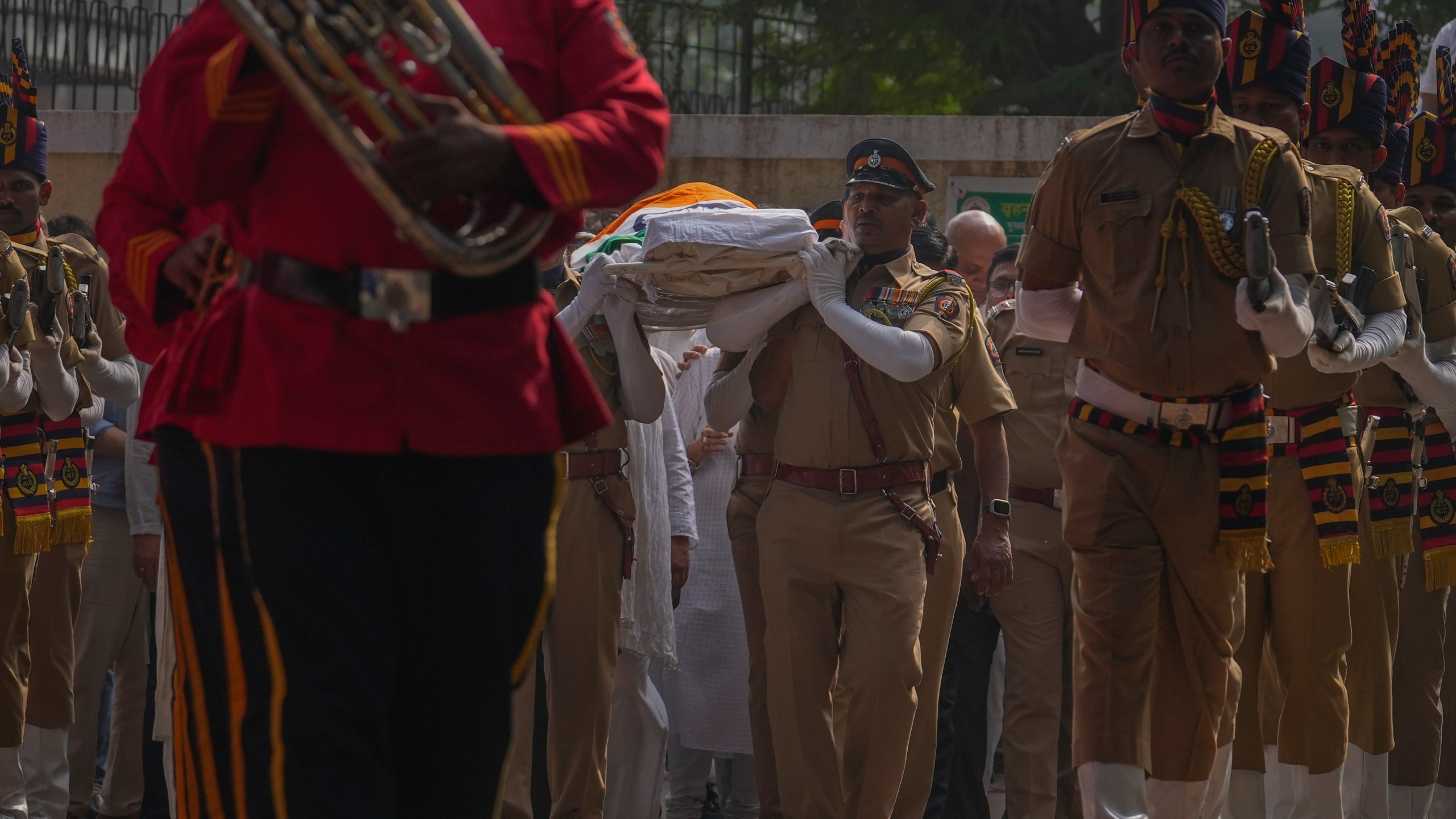 Police officers carry the body of Shyam Benegal, a renowned Indian filmmaker who passed away on Monday, during Benegal's funeral in Mumbai, India, Tuesday, Dec. 24, 2024. (AP Photo/Rafiq Maqbool)