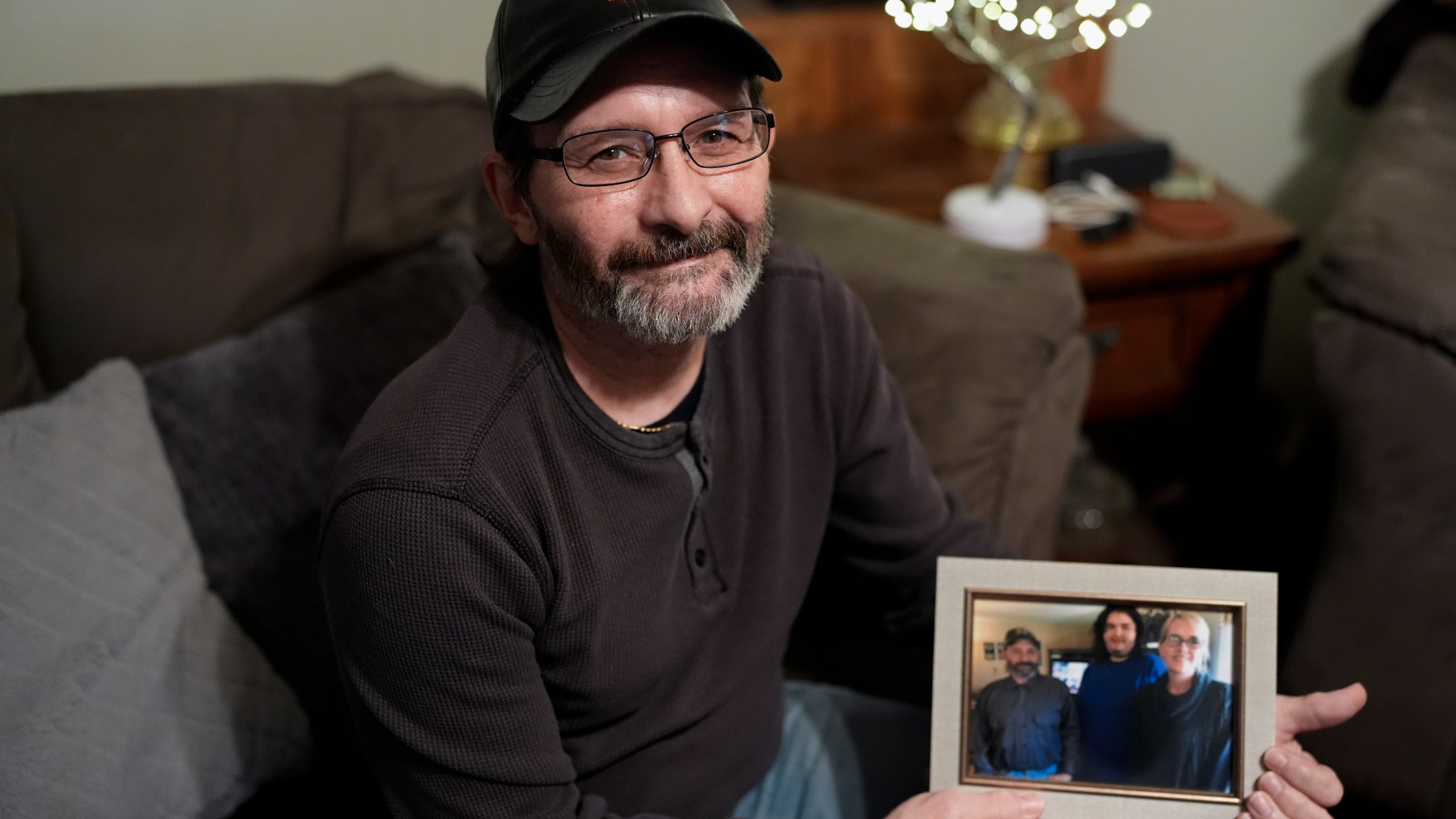 Jerry Barnett holds a picture of his wife and son on Nov. 22, 2024, in Johnson City, Tenn. Barnett's wife, Sibrina, died trying to escape flood waters caused by Hurricane Helene in September, near the plastics factory where she cleaned offices once a week. (AP Photo/George Walker IV)