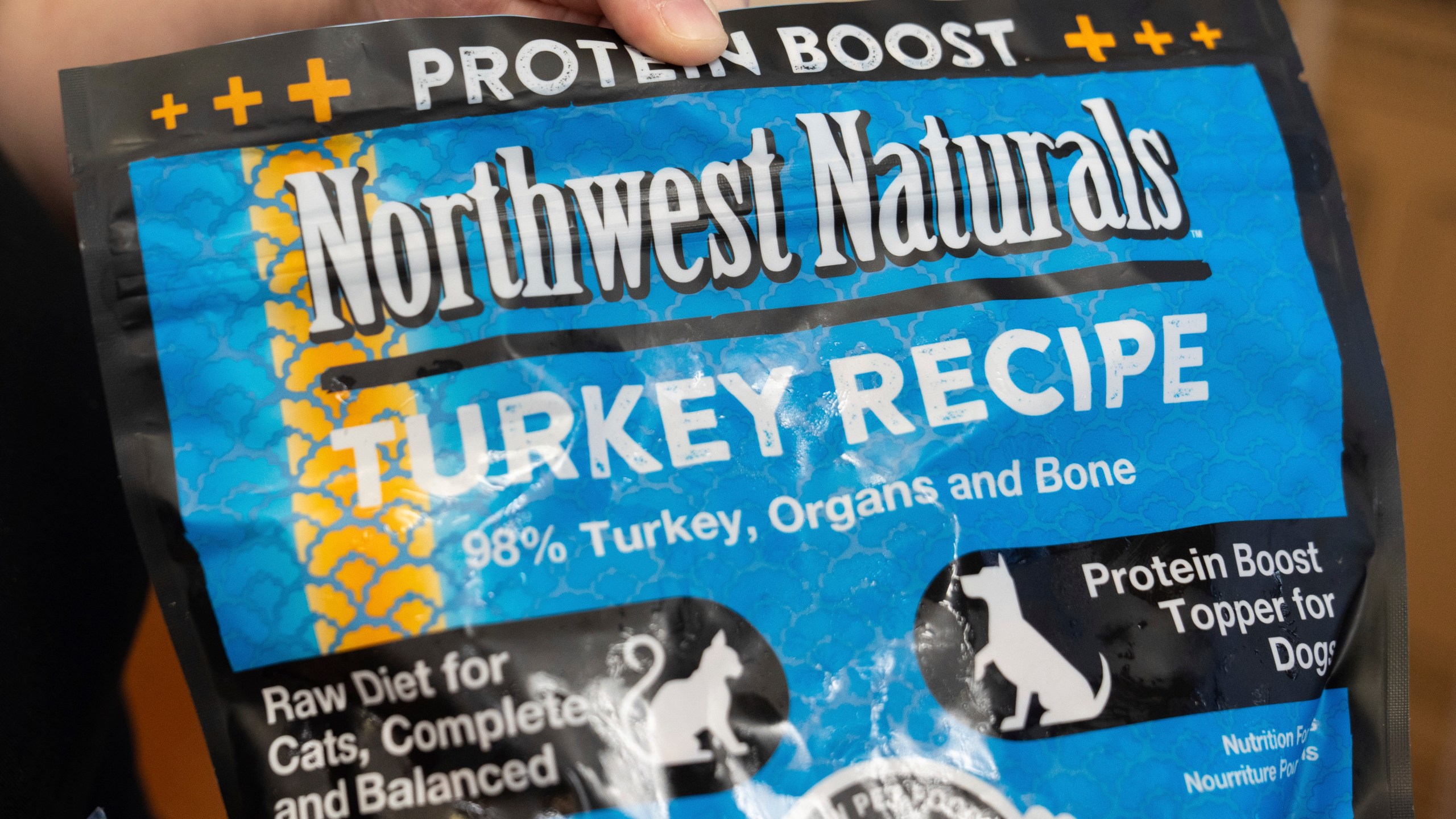 A pet store employee holds a bag of Northwest Naturals 2-pound Feline Turkey Recipe raw frozen pet food in Tigard, Ore., on Thursday, Dec. 26, 2024, after it was taken off the shelves as part of a voluntary recall by the manufacturer. (AP Photo/Jenny Kane)