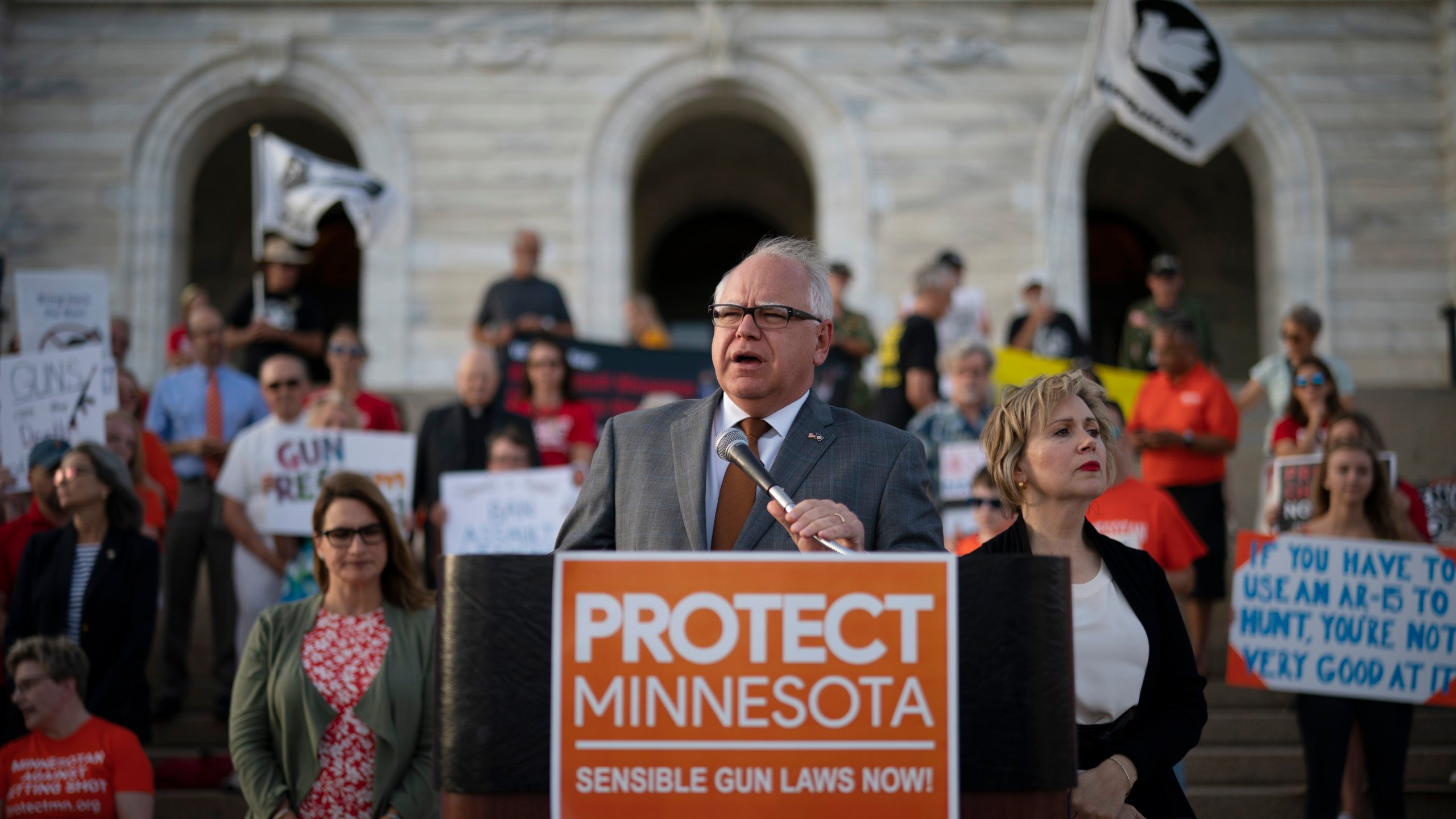 FILE - Gov. Tim Walz speaks before a crowd gathered for a rally on the steps of the state Capitol in St. Paul, Minn., Wednesday evening, Aug. 7, 2019. Lt. Gov. Peggy Flanagan, center left, and his wife Gwen Walz, center right, stand by him. (Jeff Wheeler/Star Tribune via AP, File)