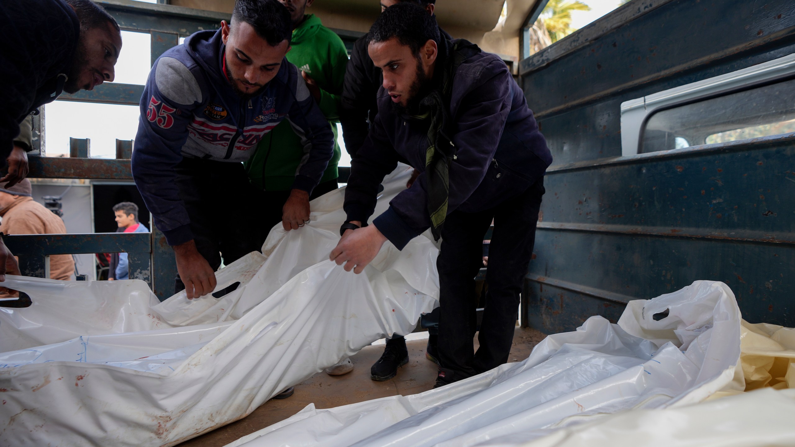 Palestinians carry white sacks containing the bodies of those killed in overnight Israeli airstrikes on the Maghazi refugee camp, at Al-Aqsa Hospital, in Deir al-Balah, central Gaza Strip, Saturday, Dec. 28, 2024. (AP Photo/Abdel Kareem Hana)