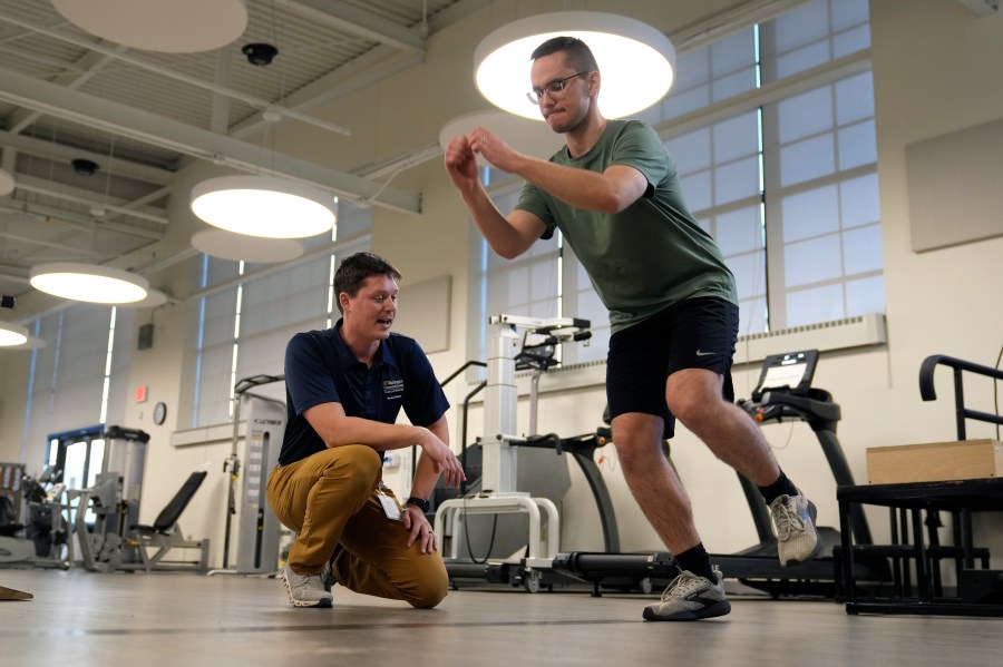 Physical therapist Tyler Detmer, left, works with patient Jacob Bullard at WashU, Monday, Dec. 16, 2024, in St. Louis. (AP Photo/Jeff Roberson)