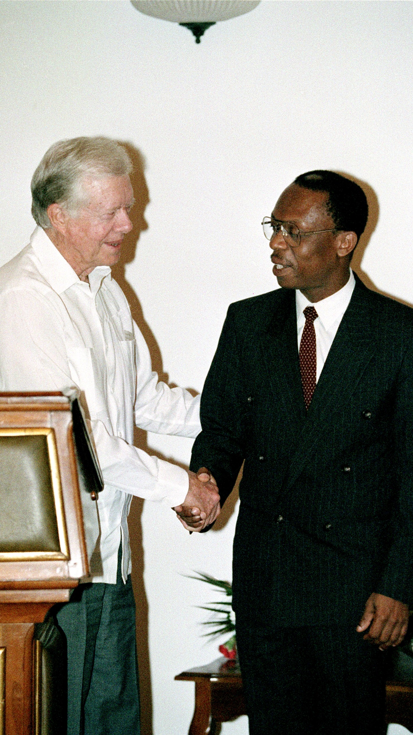 FILE - Former President Jimmy Carter shakes hands with Haitian President Jean-Bertrand Aristide at the Presidential Palace in Port-au-Prince in Haiti, Feb. 23, 1995. (AP Photo/Andrew Innerarity, File)