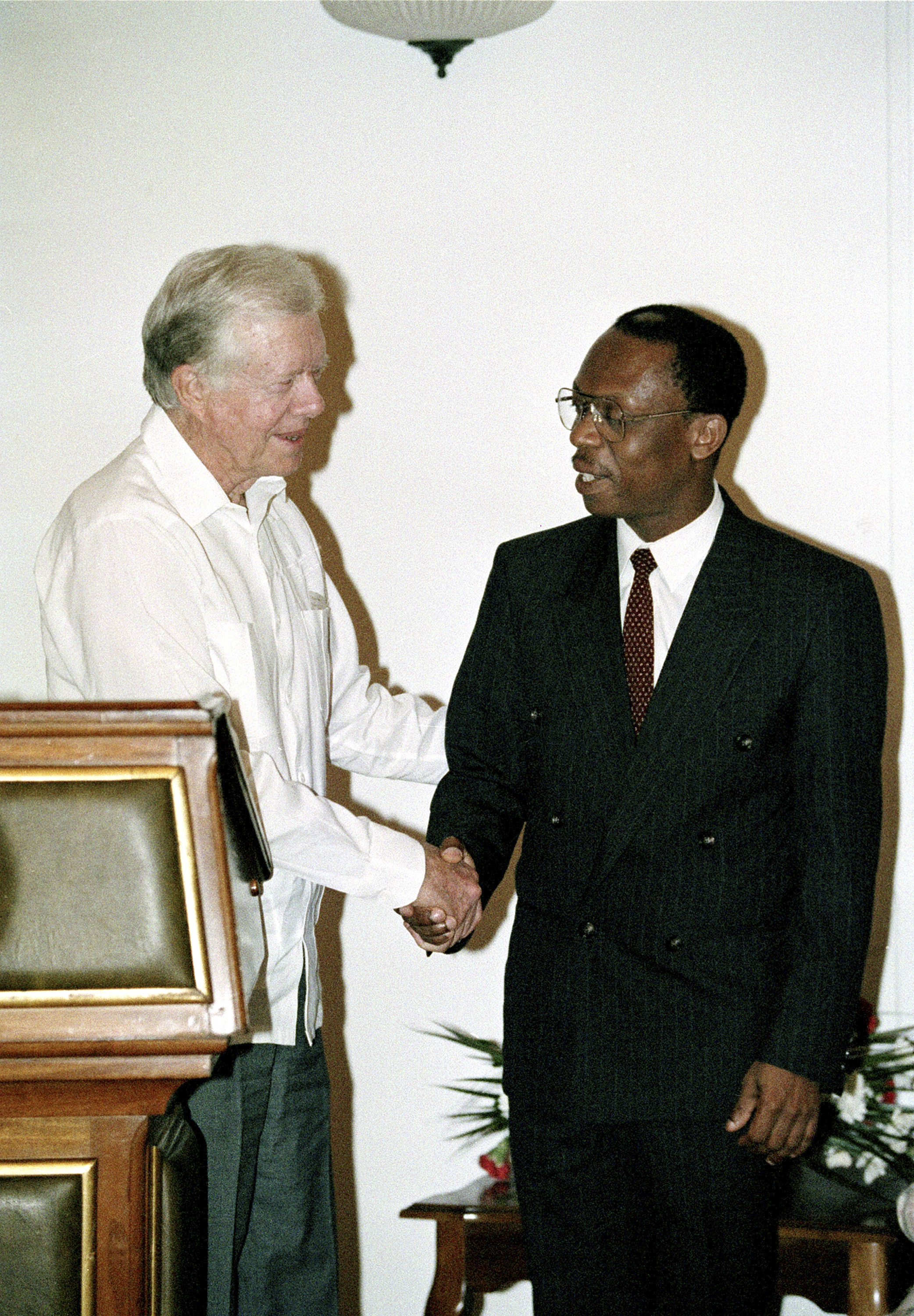 FILE - Former President Jimmy Carter shakes hands with Haitian President Jean-Bertrand Aristide at the Presidential Palace in Port-au-Prince in Haiti, Feb. 23, 1995. (AP Photo/Andrew Innerarity, File)