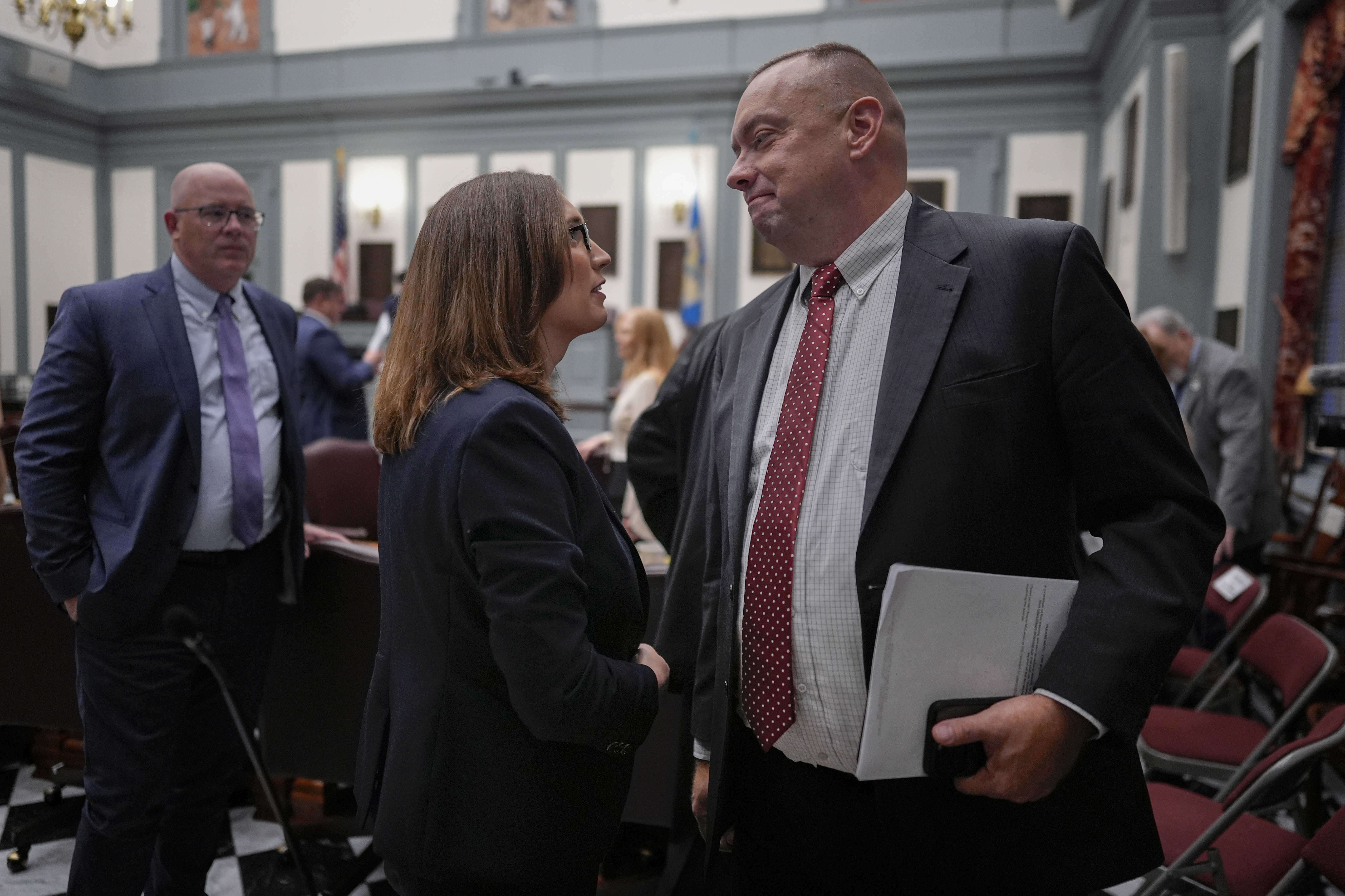 U.S.-Rep.-elect Sarah McBride, D-Del., center, talks with Delaware Senate Republican Minority Whip Brian Pettyjohn from the 19th district on the Senate floor on McBride's last day as a Delaware state senator at the Delaware Legislative Hall in Dover, Del., Monday, Dec. 16, 2024. (AP Photo/Carolyn Kaster)