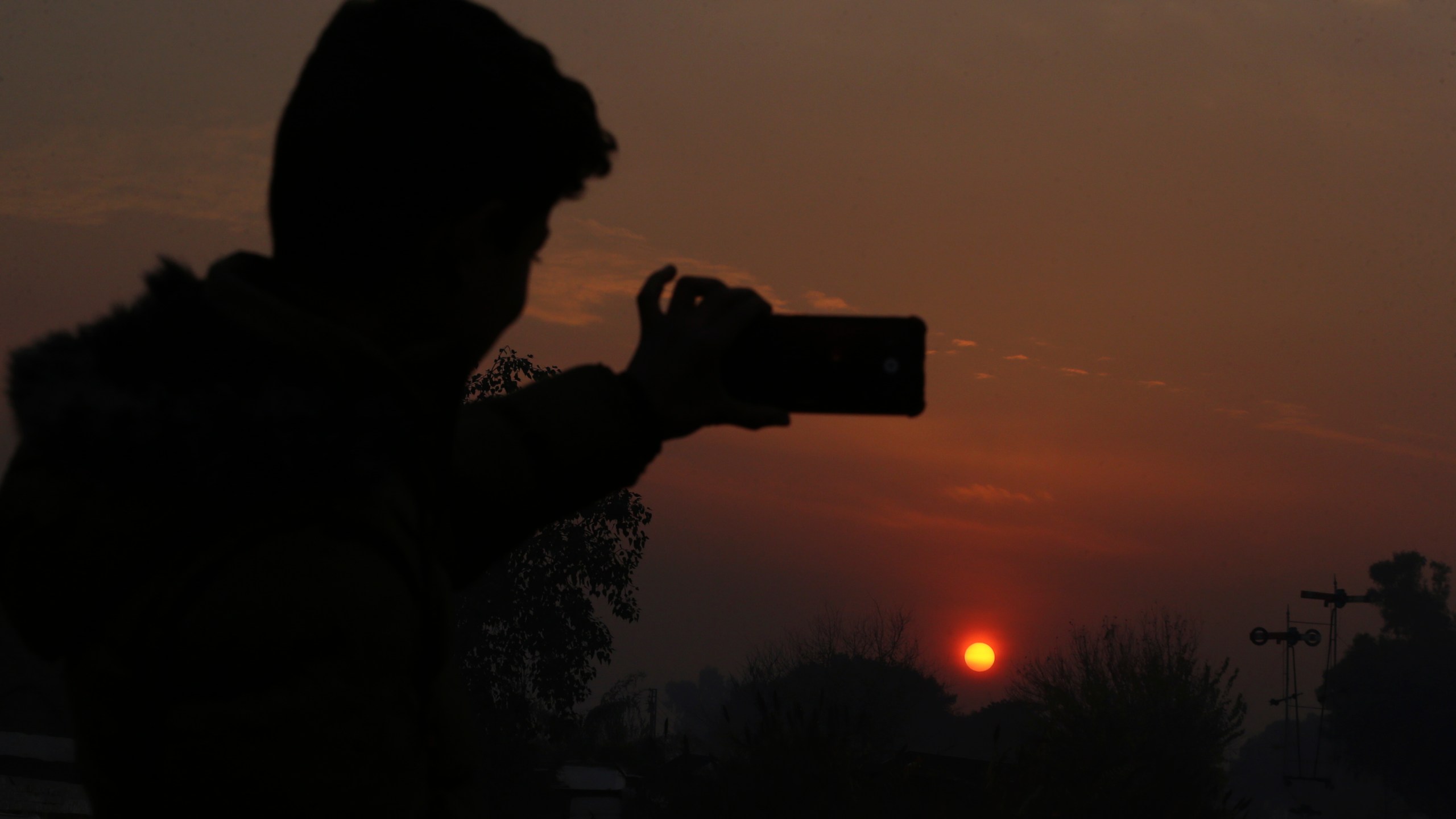 A Pakistani man take a selfie photo while the last sunset of 2024 hangs over the city of Peshawar, Pakistan, Tuesday, Dec. 31, 2024. (AP Photo/Mohammad Sajjad)