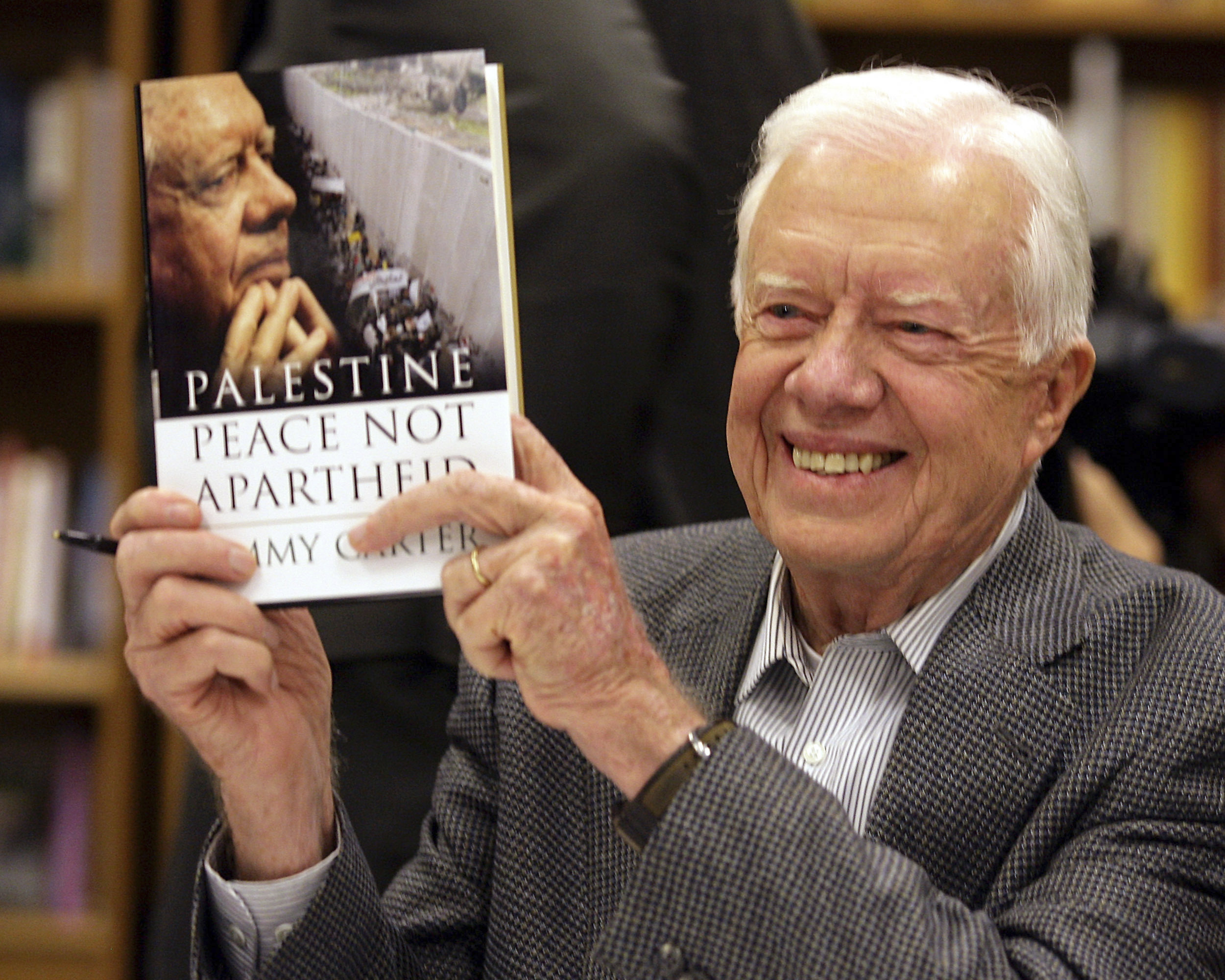 FILE - Former President Jimmy Carter holds a copy of his book, "Palestine: Peace, Not Apartheid," prior to a book signing at the Changing Hands bookstore on Dec. 12, 2006, in Tempe, Ariz. (AP Photo/Paul Connors, File)