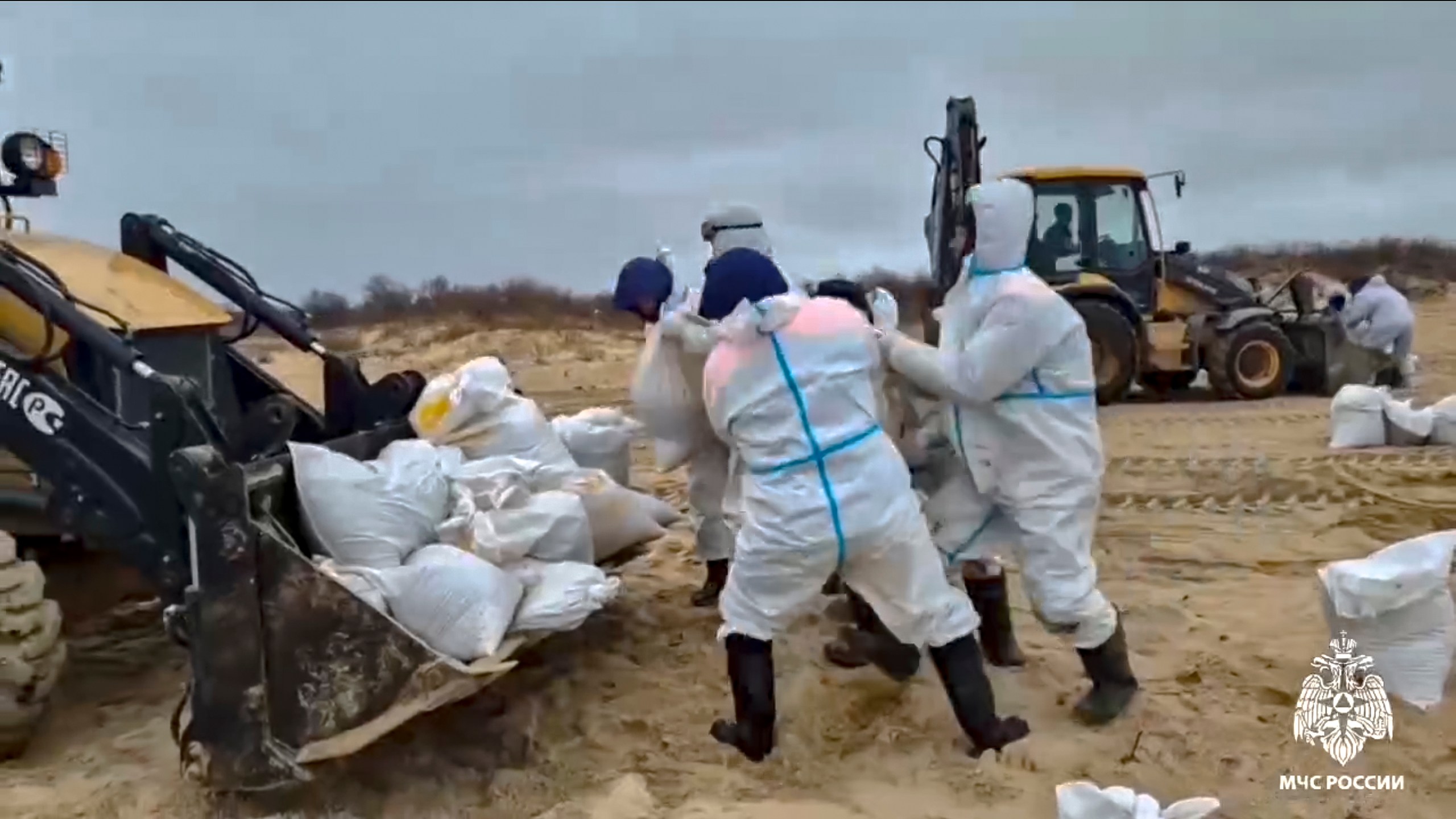 In this photo taken from video released by Russian Emergency Ministry Press Service on Saturday, Jan. 4, 2025, rescuers and volunteers work to clean up tons of fuel oil that spilled out of two storm-stricken tankers more than two weeks ago in the Kerch Strait, in Russia's southern Krasnodar region. (Russian Emergency Ministry Press Service via AP)