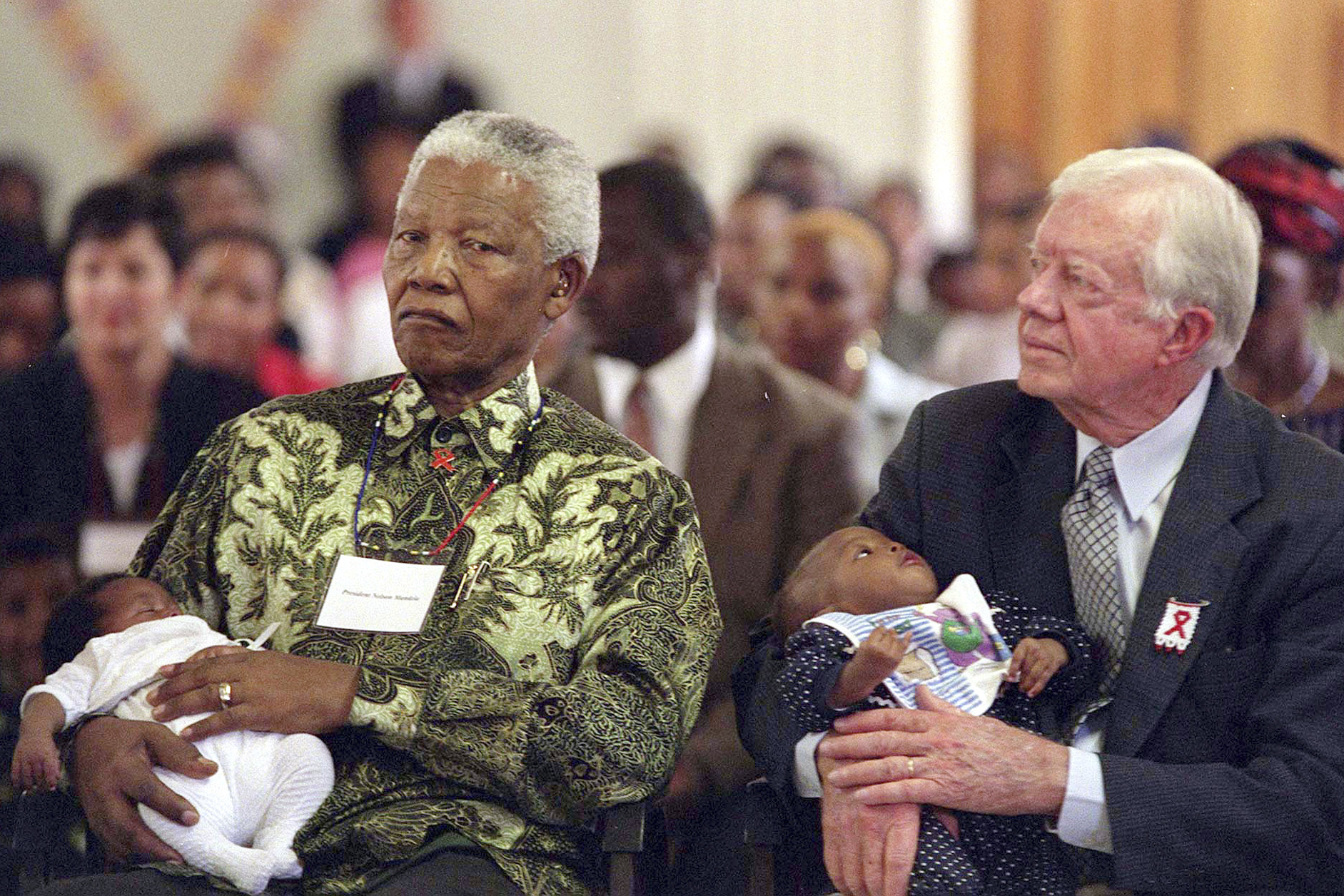 FILE - Former South African President Nelson Mandela, left, and former U.S. President Jimmy Carter, right, hold HIV-positive babies at the Zola Clinic in Soweto, March 7, 2002. (AP Photo/Nonthemba Kwela, File)