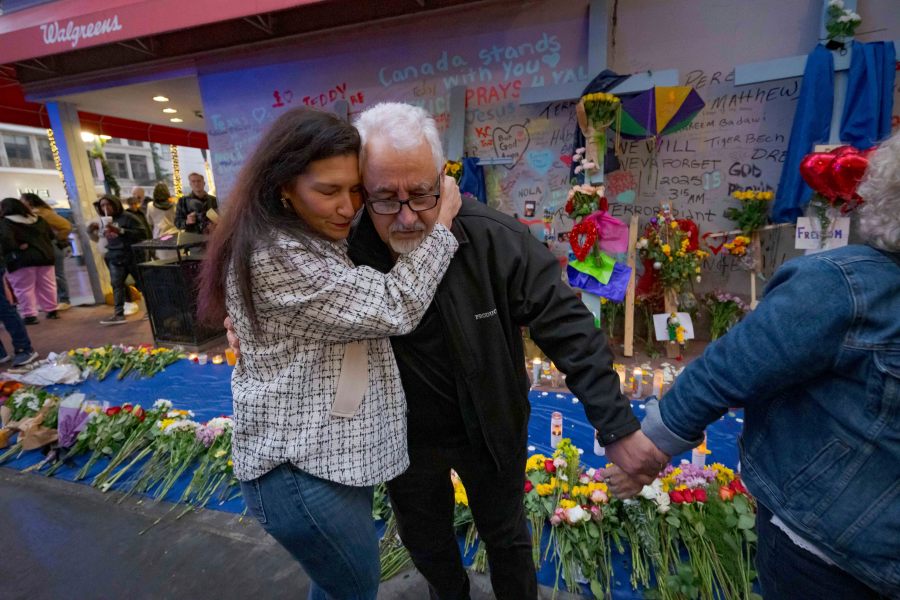 Long Island, New York residents Louis Tenedorio is hugged by family friend Angelique Whittington, left, while holding the hand of his wife, Cathy Tenedorio, by a memorial Bourbon Street and Canal Street in New Orleans, Saturday, Jan. 4, 2025, where their son, Matthew Tenedorio, was killed as one of the victims of the New Year's Day deadly truck attack and shooting. (AP Photo/Matthew Hinton)