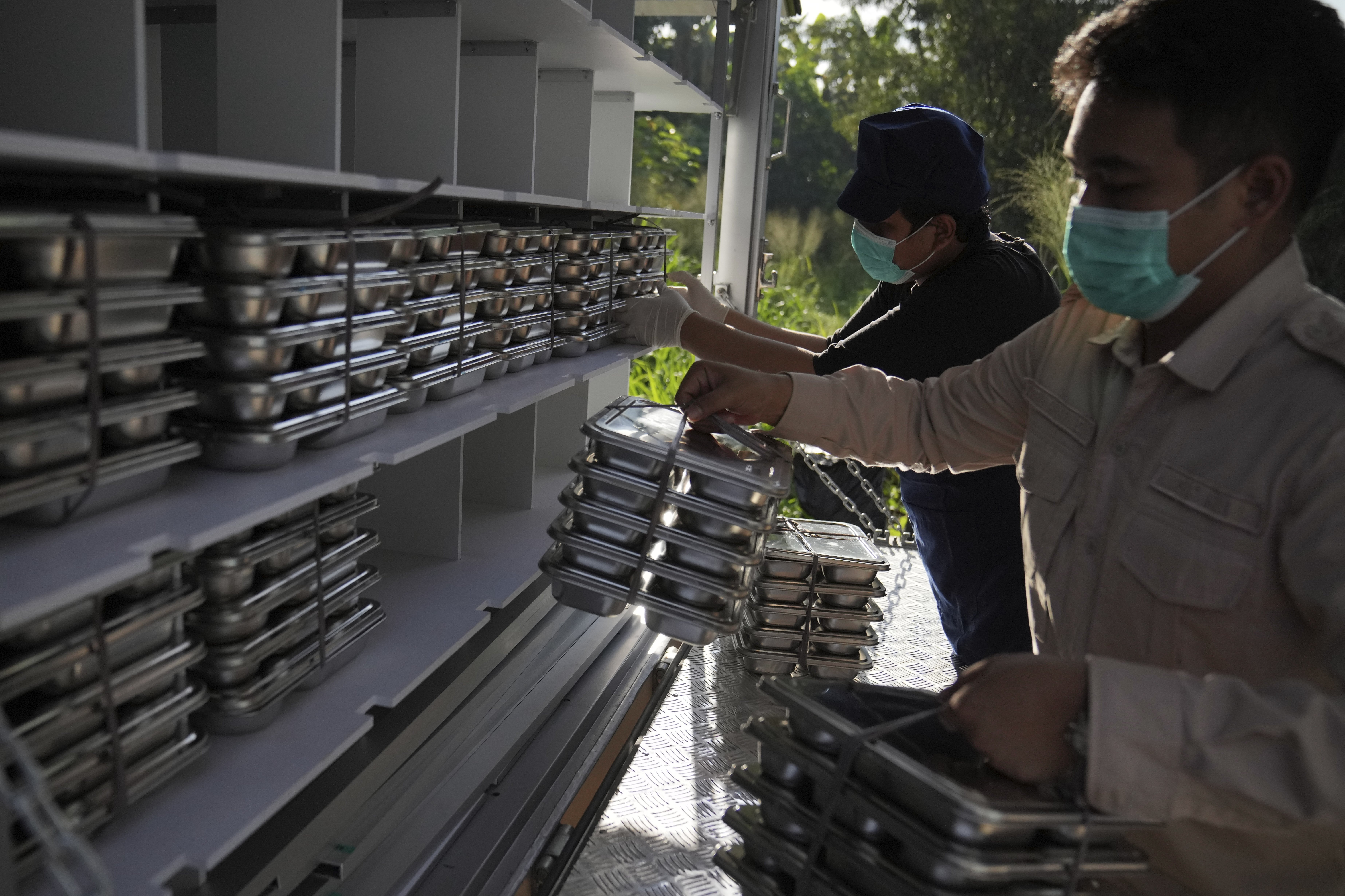 Workers load food containers to be distributed to schools during the kick off of President Prabowo Subianto's ambitious free meal program to feed children and pregnant women nationwide despite critics saying that its required logistics could hurt Indonesia's state finances and economy, at an elementary school in Depok, West Java, Indonesia, Monday, Jan. 6, 2025. (AP Photo/Dita Alangkara)