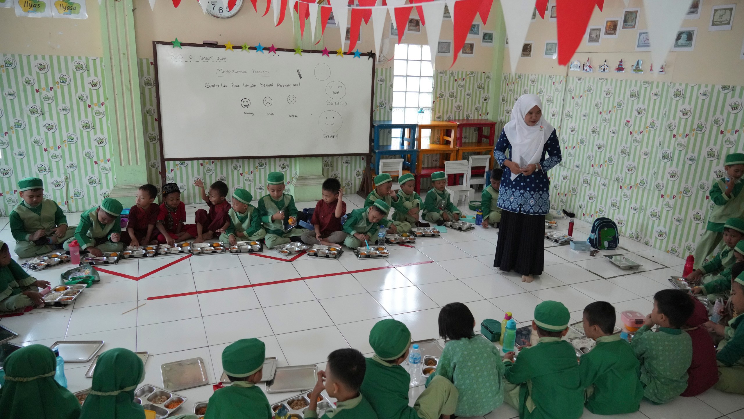 Students sit on the floor as they have their meals during the kick off of President Prabowo Subianto's ambitious free meal program to feed children and pregnant women nationwide despite critics saying that its required logistics could hurt Indonesia's state finances and economy at Early Childhood Education and Development in Jakarta, Indonesia, Monday, Jan. 6, 2025. (AP Photo/Achmad Ibrahim)