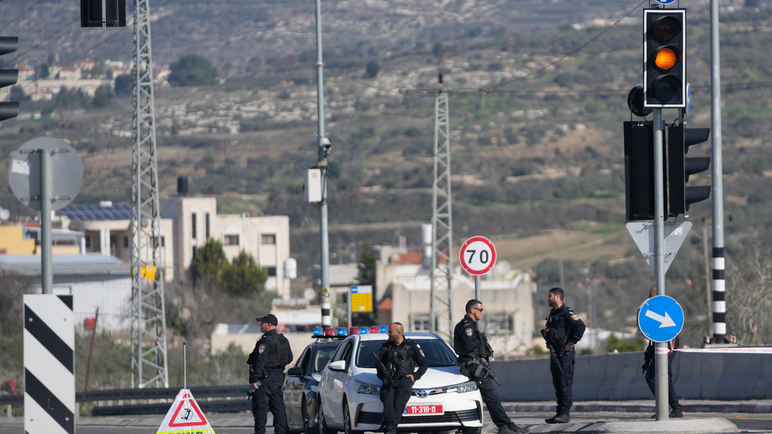 Israeli policemen block a main road after gunmen opened fire on cars and a bus carrying Israelis in the occupied West Bank, killing at least three people, near the Palestinian village of Al-Funduq, Monday, Jan. 6, 2025. (AP Photo/Nasser Nasser)