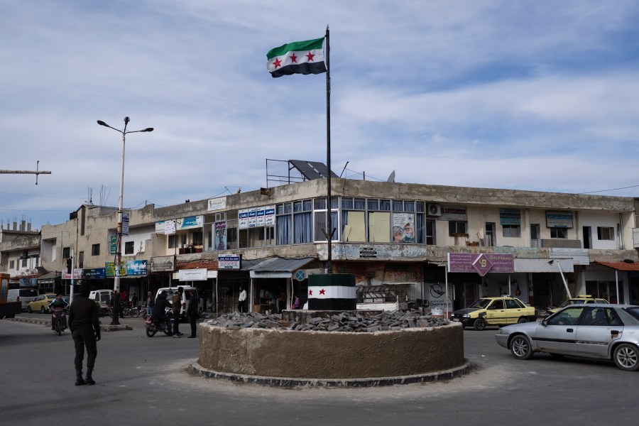 Cars drive past a roundabout hoisting the new Syrian flag after the ousting of the Assad regime, in Salam City, formerly called Baath City after the ruling party, in Quneitra, Syria, Sunday, Jan. 5, 2025. (AP Photo/Mosa'ab Elshamy)