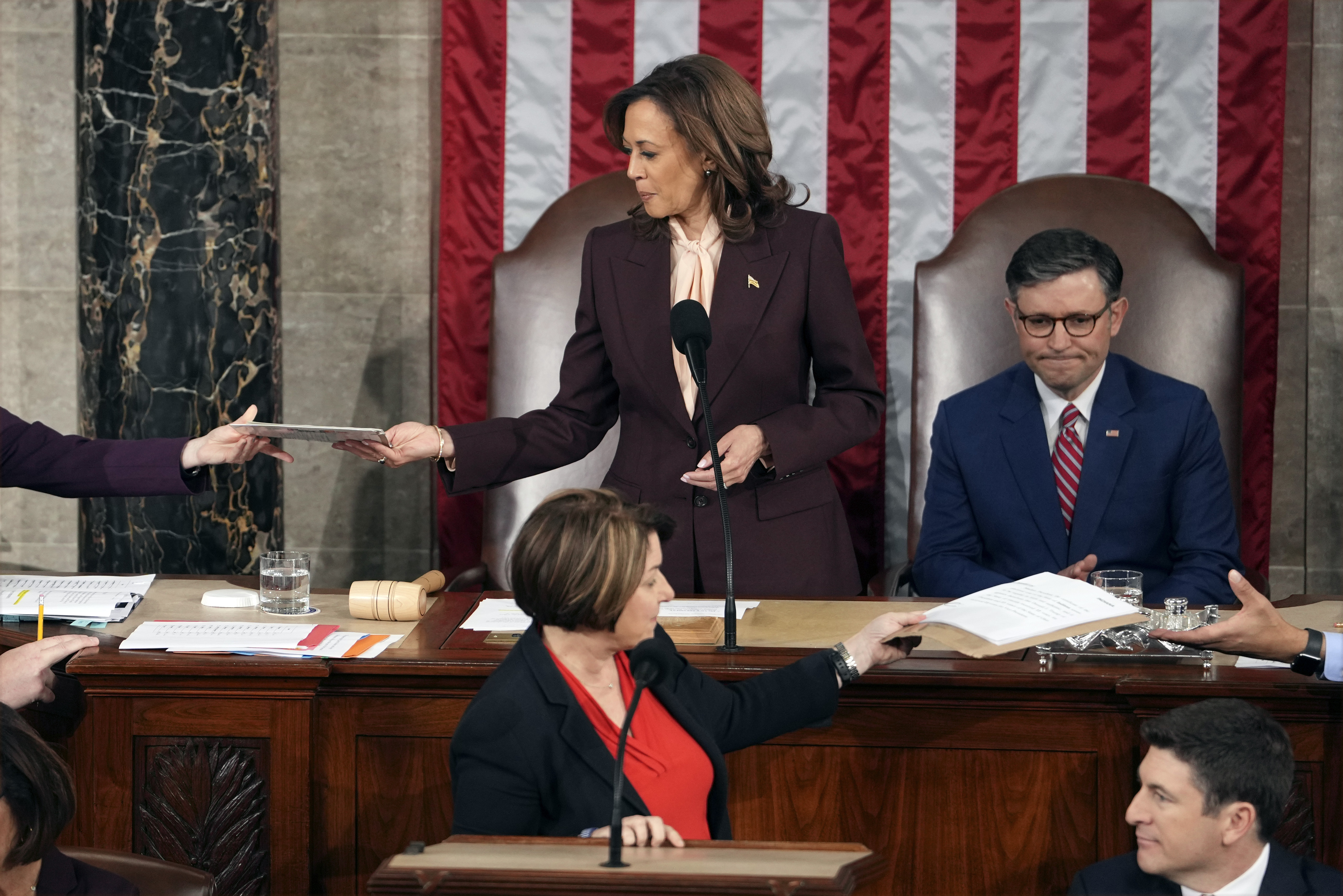 Vice President Kamala Harris is handed a certification as House Speaker Mike Johnson of La., watches while teller Sen. Amy Klobuchar, D-Minn., stands at the clerk's podium as a joint session of Congress convenes to confirm the Electoral College votes, affirming President-elect Donald Trump's victory in the presidential election, Monday, Jan. 6, 2025, at the U.S. Capitol in Washington. (AP Photo/Matt Rourke)