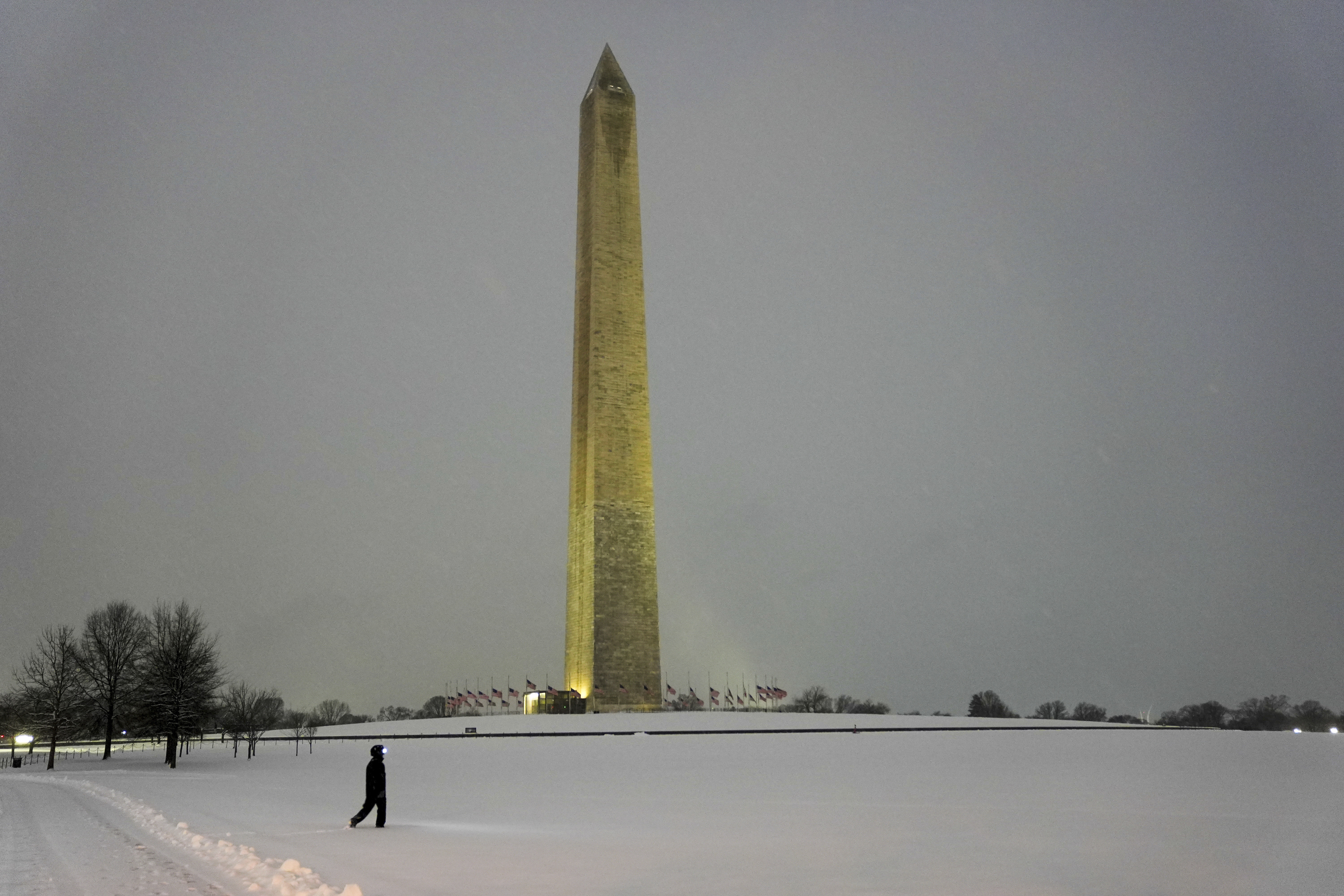 A person walks near the Washington Monument during a winter snow storm in Washington, Monday, Jan. 6, 2025. (AP Photo/Matt Rourke)