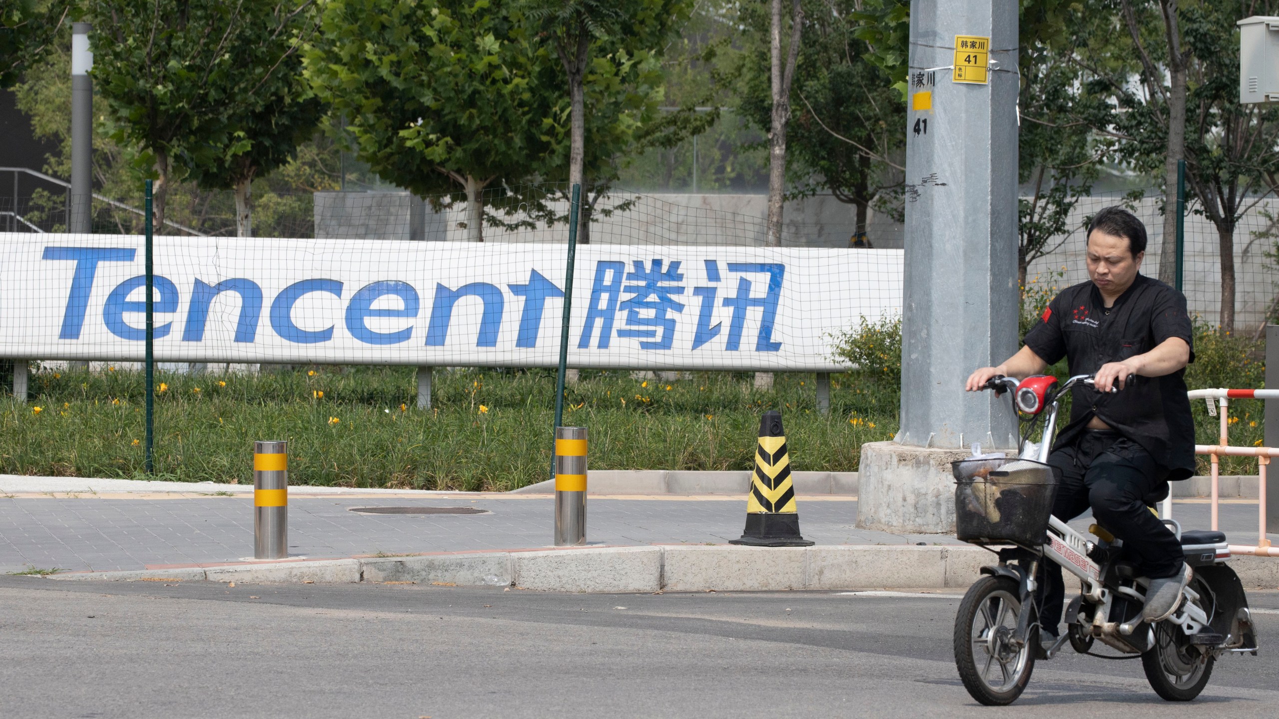 FILE - A man rides past the Tencent headquarters in Beijing, China on Aug. 7, 2020. (AP Photo/Ng Han Guan, File)