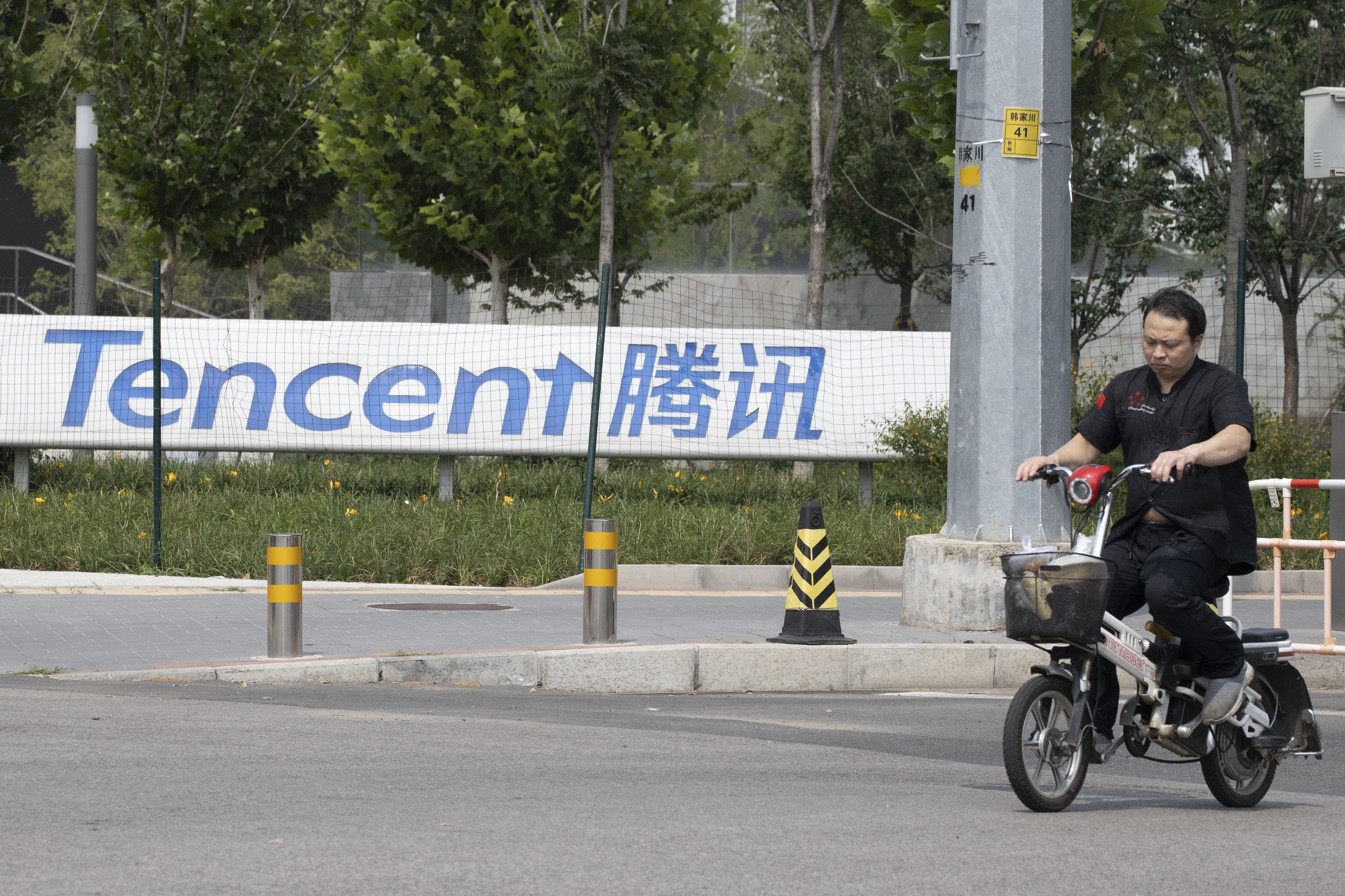 FILE - A man rides past the Tencent headquarters in Beijing, China on Aug. 7, 2020. (AP Photo/Ng Han Guan, File)