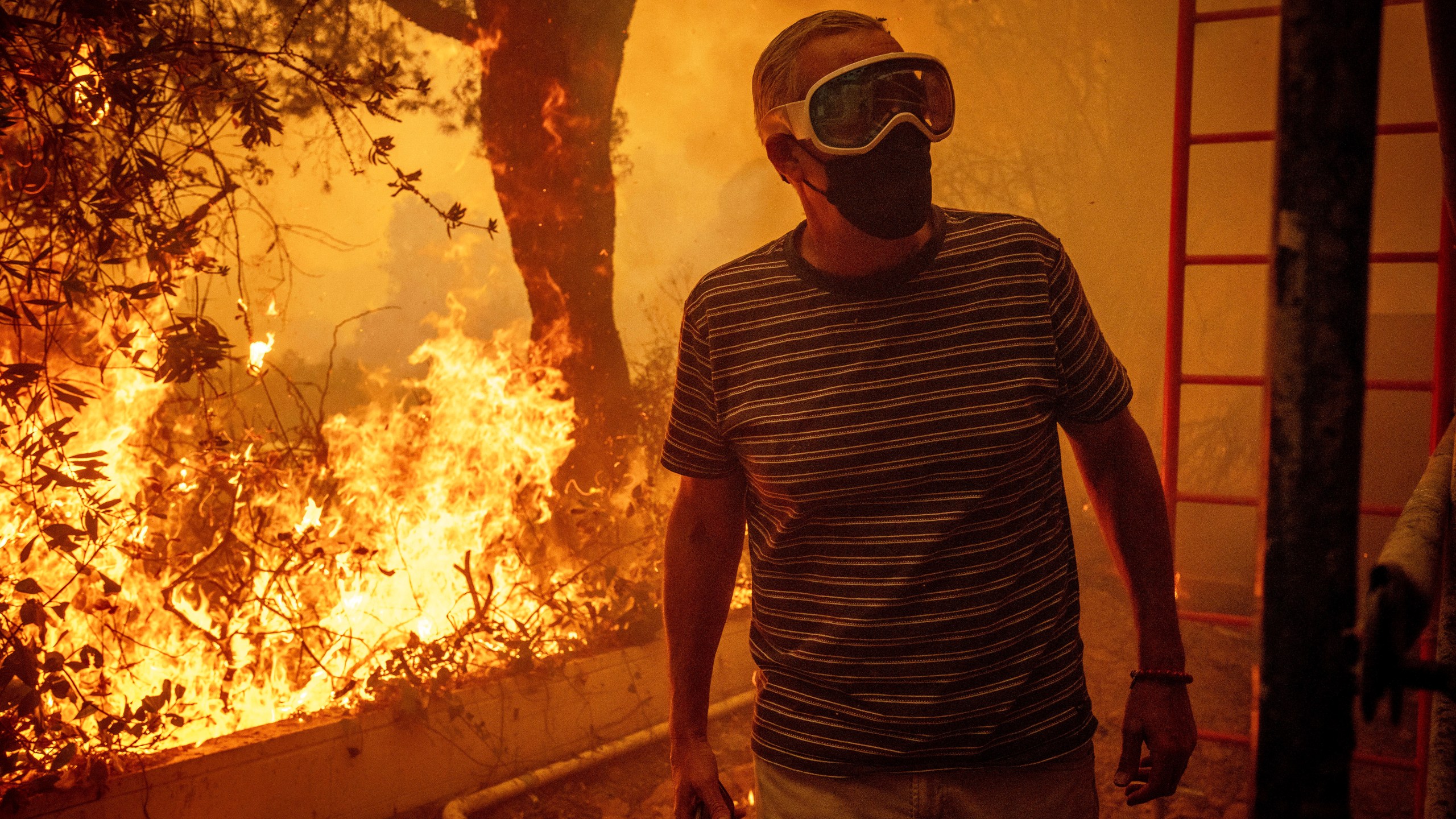 Will Adams watches as flames from the Palisades Fire close in on his property in the Pacific Palisades neighborhood of Los Angeles, Tuesday, Jan. 7, 2025. (AP Photo/Ethan Swope)