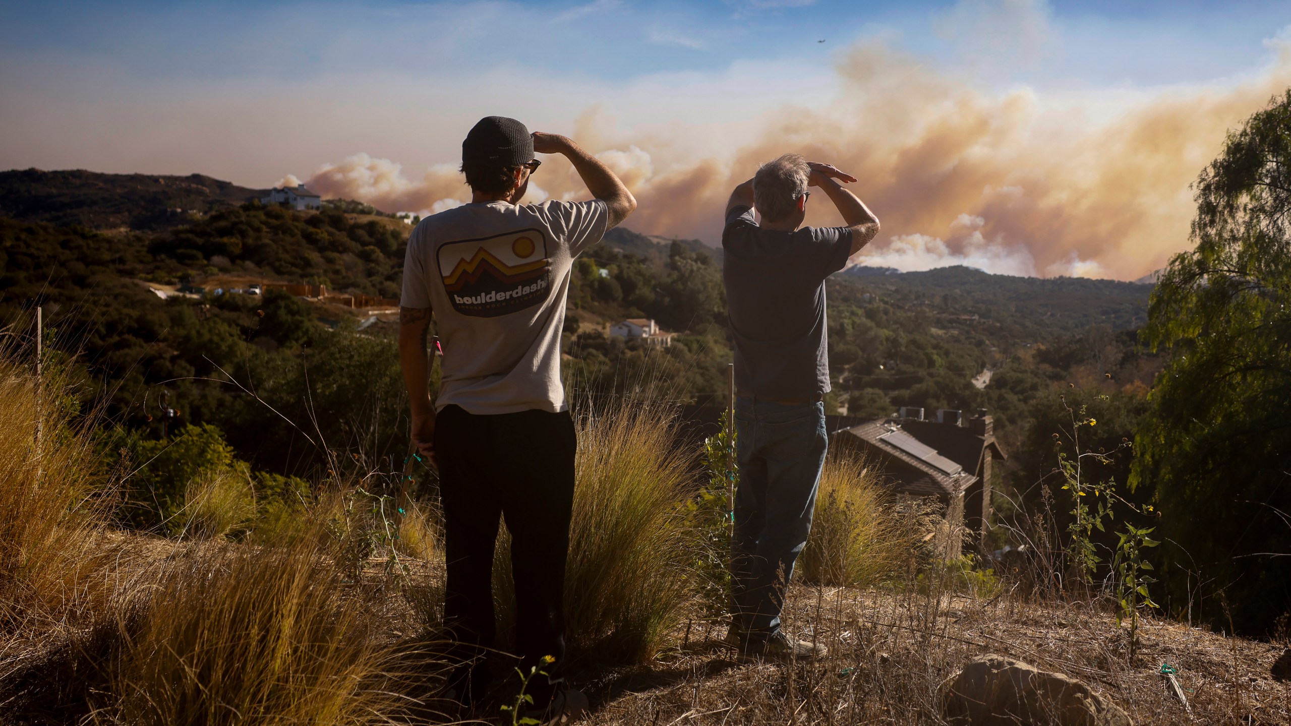 Topanga Canyon inhabitants look on as the Palisades Fire burns in the hills between Pacific Palisades and Malibu Wednesday, Jan. 8, 2025 in Topanga, Calif. (AP Photo/Etienne Laurent)