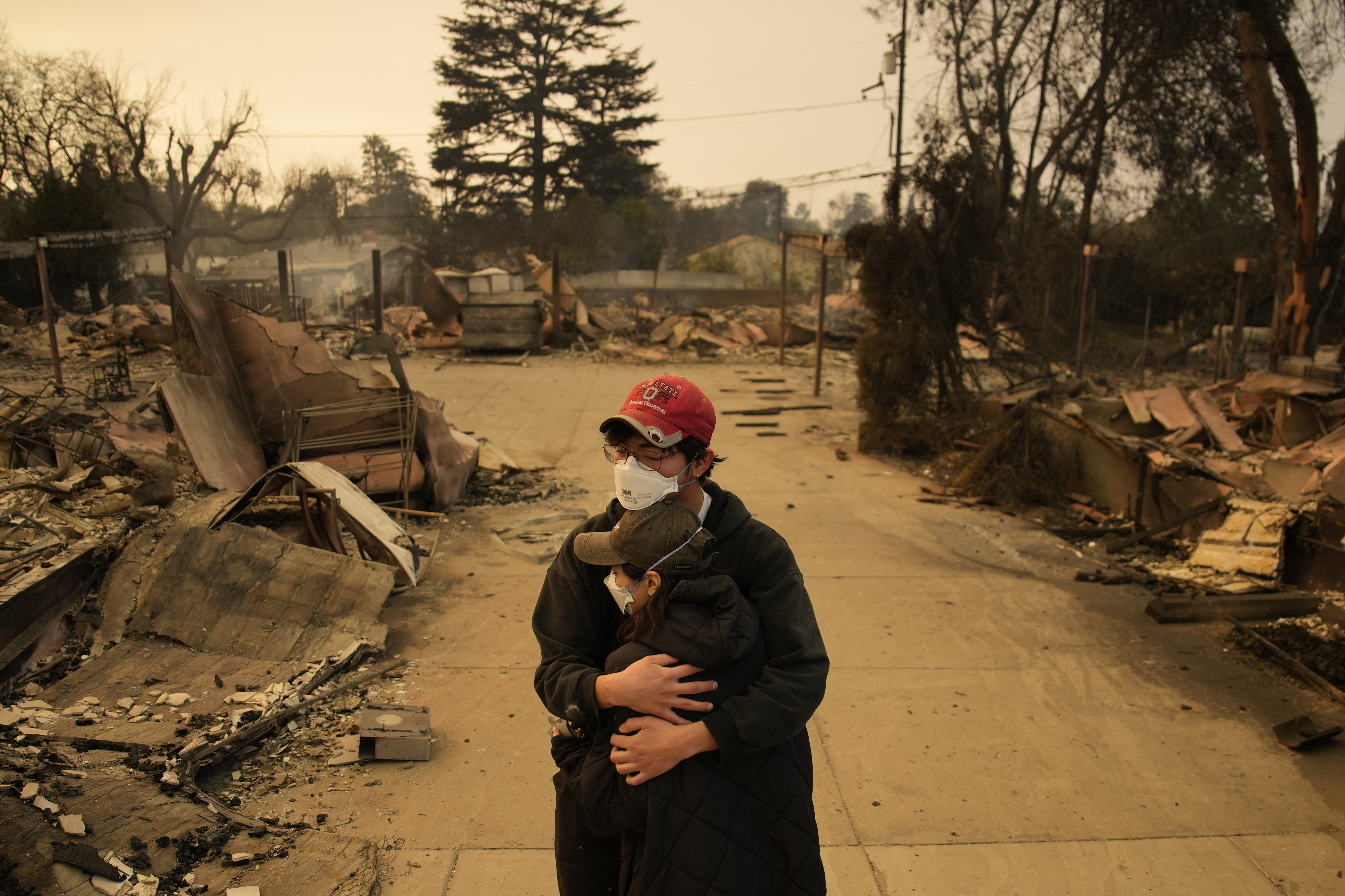 Ari Rivera, rear, Anderson Hao hold each other in front of their destroyed home in Altadena, Calif., Thursday, Jan. 9, 2025. (AP Photo/John Locher)