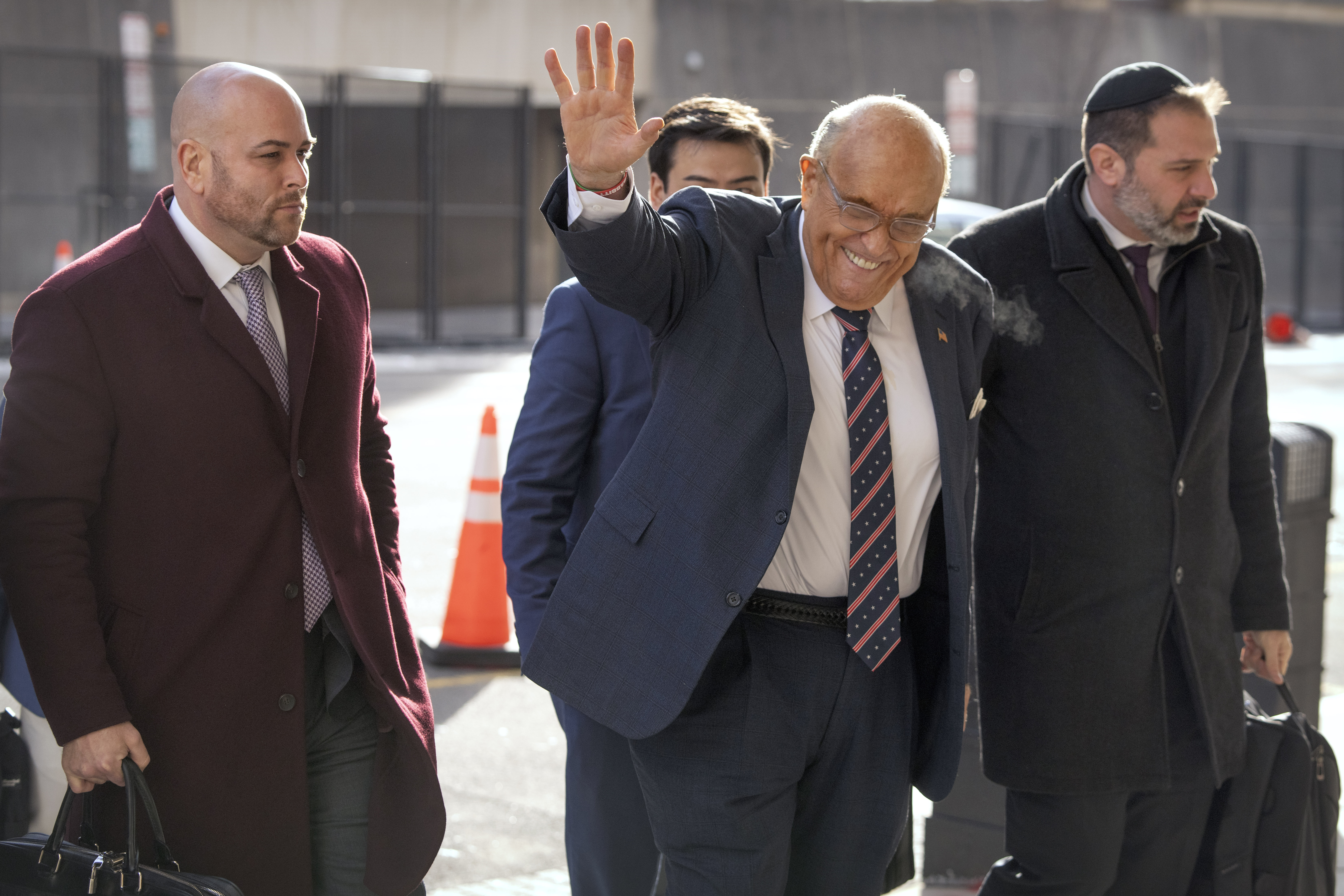 Rudy Giuliani, second from right, waves as he arrives at federal court in Washington, Friday, Jan. 10, 2025. (AP Photo/Mark Schiefelbein)