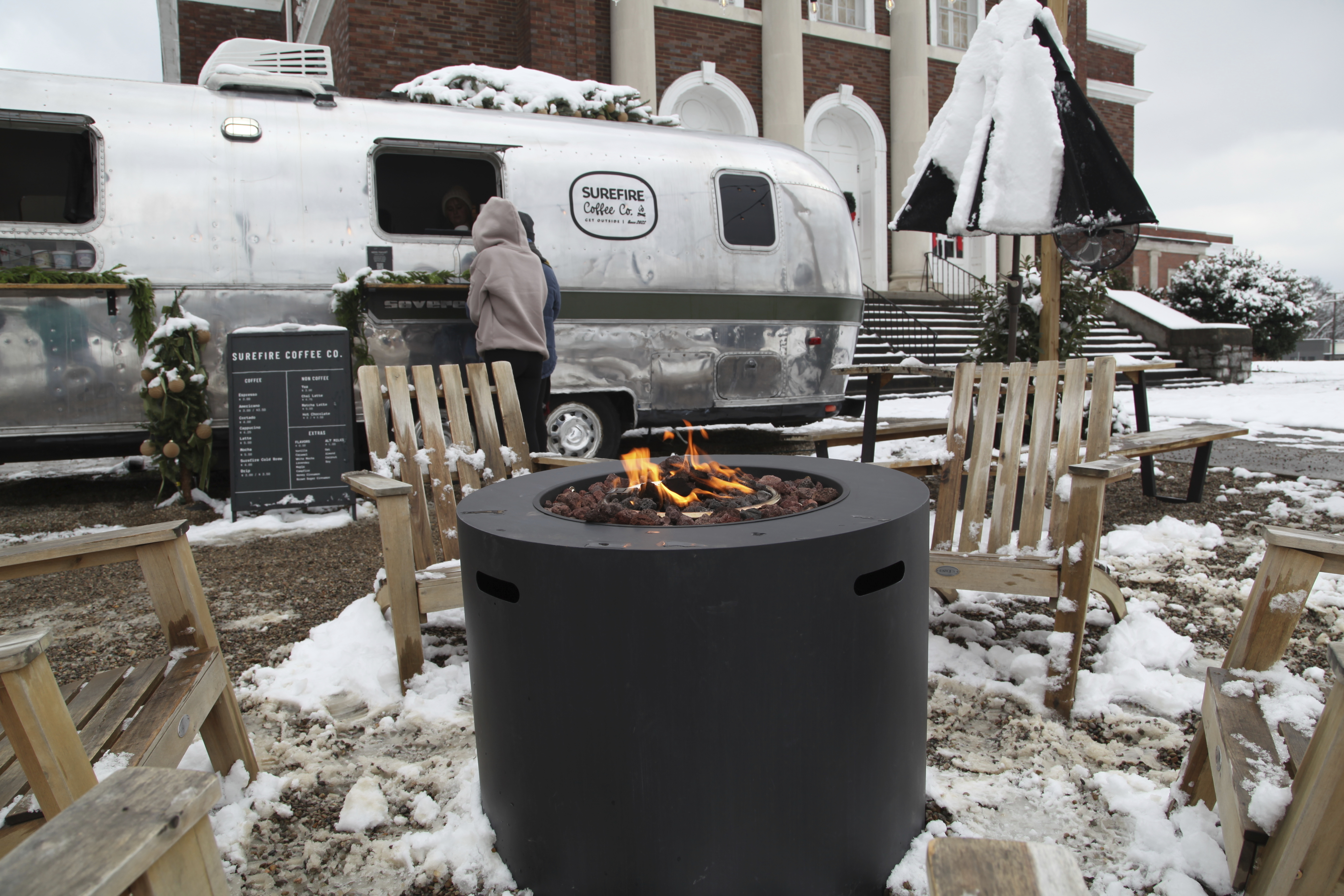 CORRECTS NAME OF RESTAURANT - People drink coffee outside of Surefire Coffee Co. after snow fell in the area in Nashville, Tenn. on Saturday, Jan.11, 2025. (AP Photo/Kristin M. Hall)