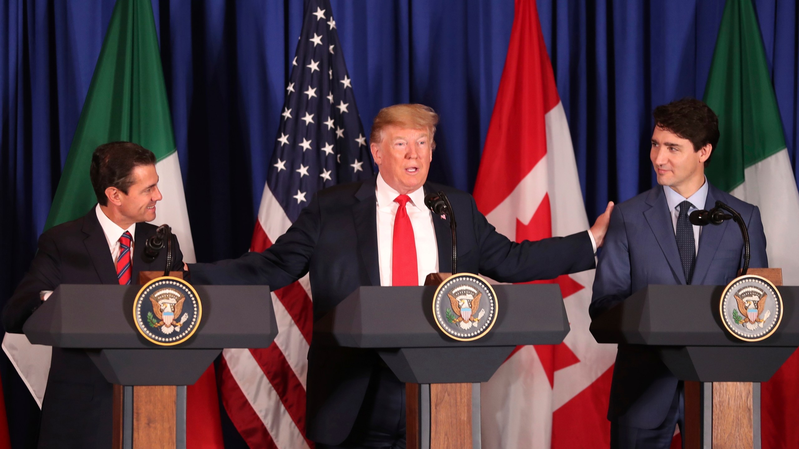 FILE - President Donald Trump, center, reaches out to Mexico's President Enrique Pena Nieto, left, and Canada's Prime Minister Justin Trudeau as they prepare to sign a new United States-Mexico-Canada Agreement that is replacing the NAFTA trade deal during a ceremony at a hotel before the start of the G20 summit in Buenos Aires, Argentina, on Nov. 30, 2018. (AP Photo/Martin Mejia, File)