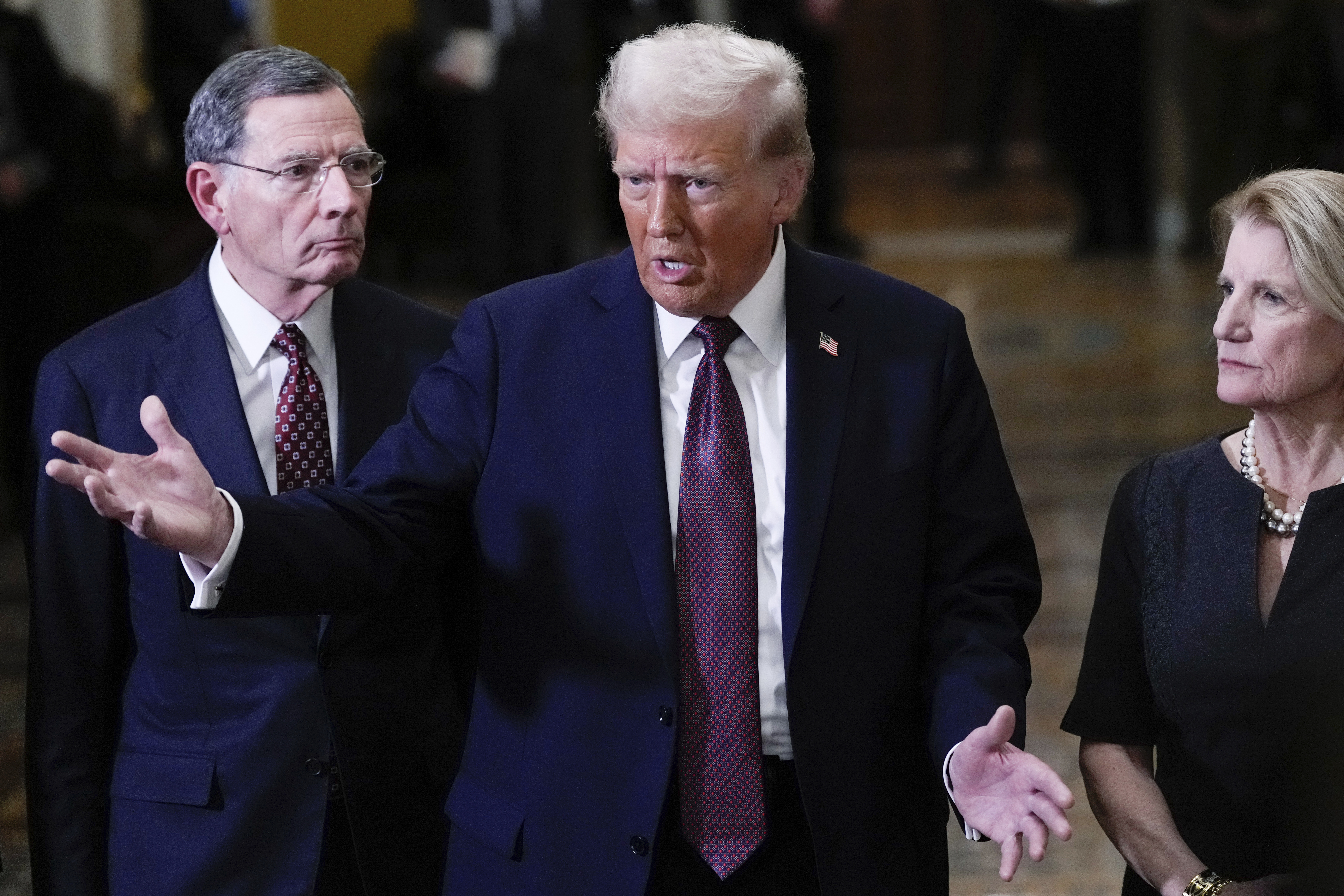 FILE - President-elect Donald Trump talks to reporters after a meeting with Republican leadership at the Capitol, Jan. 8, 2025, in Washington. At left is Sen. John Barrasso, R-Wyo., and at right is Sen. Shelley Moore Capito, R-W.Va. (AP Photo/Steve Helber, File)