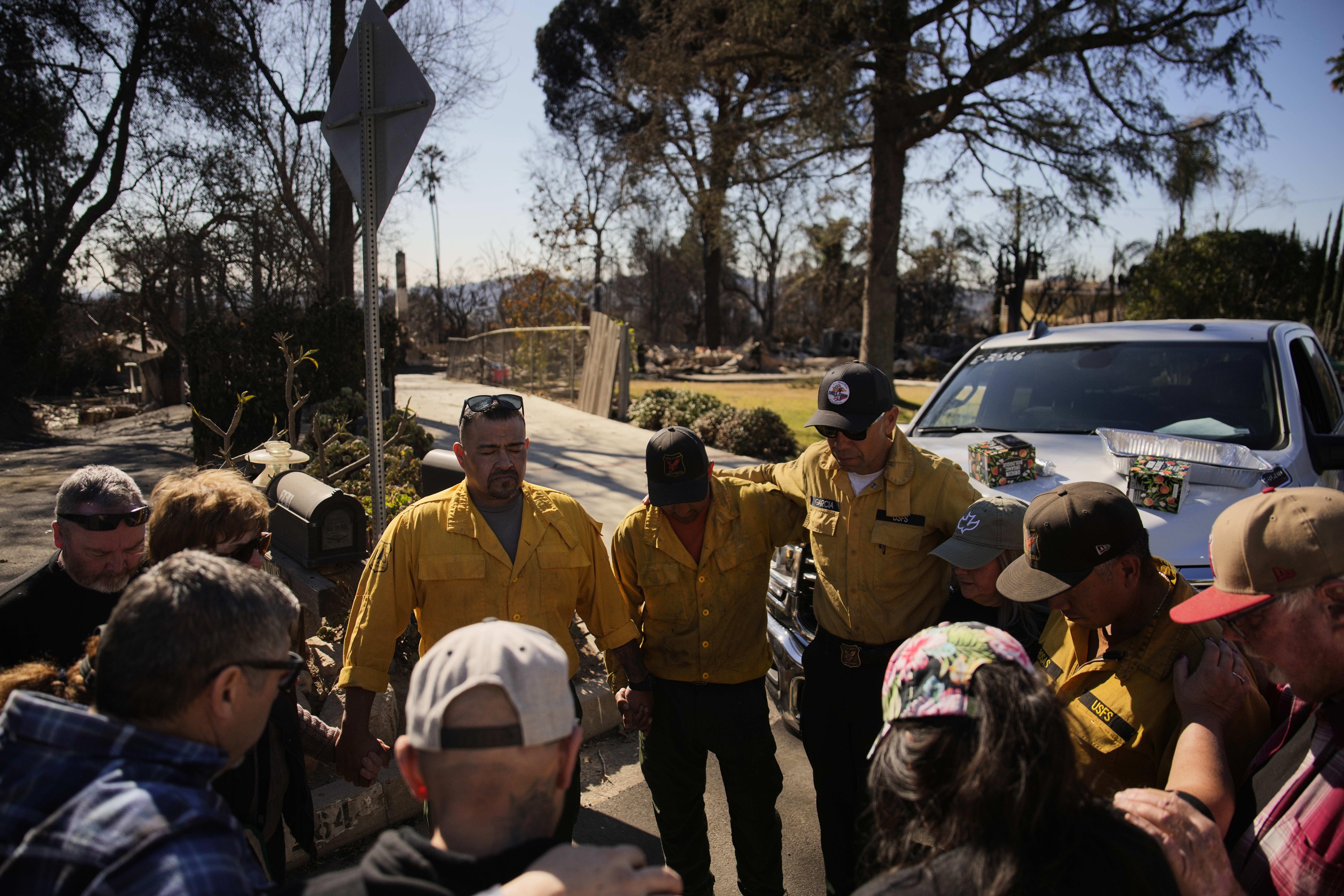 Firefighters with the U.S. Forest Service gather to pray with others, Wednesday, Jan. 15, 2025, in Altadena, Calif. (AP Photo/John Locher)