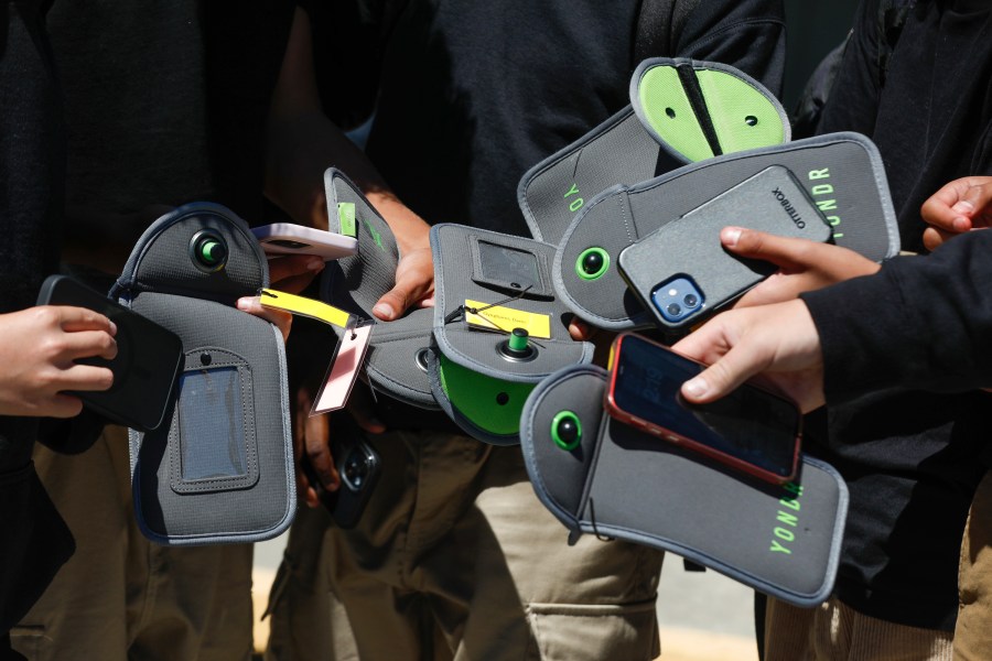 FILE - A student uses a cell phone after unlocking the pouch that secures it from use during the school day at Bayside Academy, Aug. 16, 2024, in San Mateo, Calif. (Lea Suzuki/San Francisco Chronicle via AP, File)