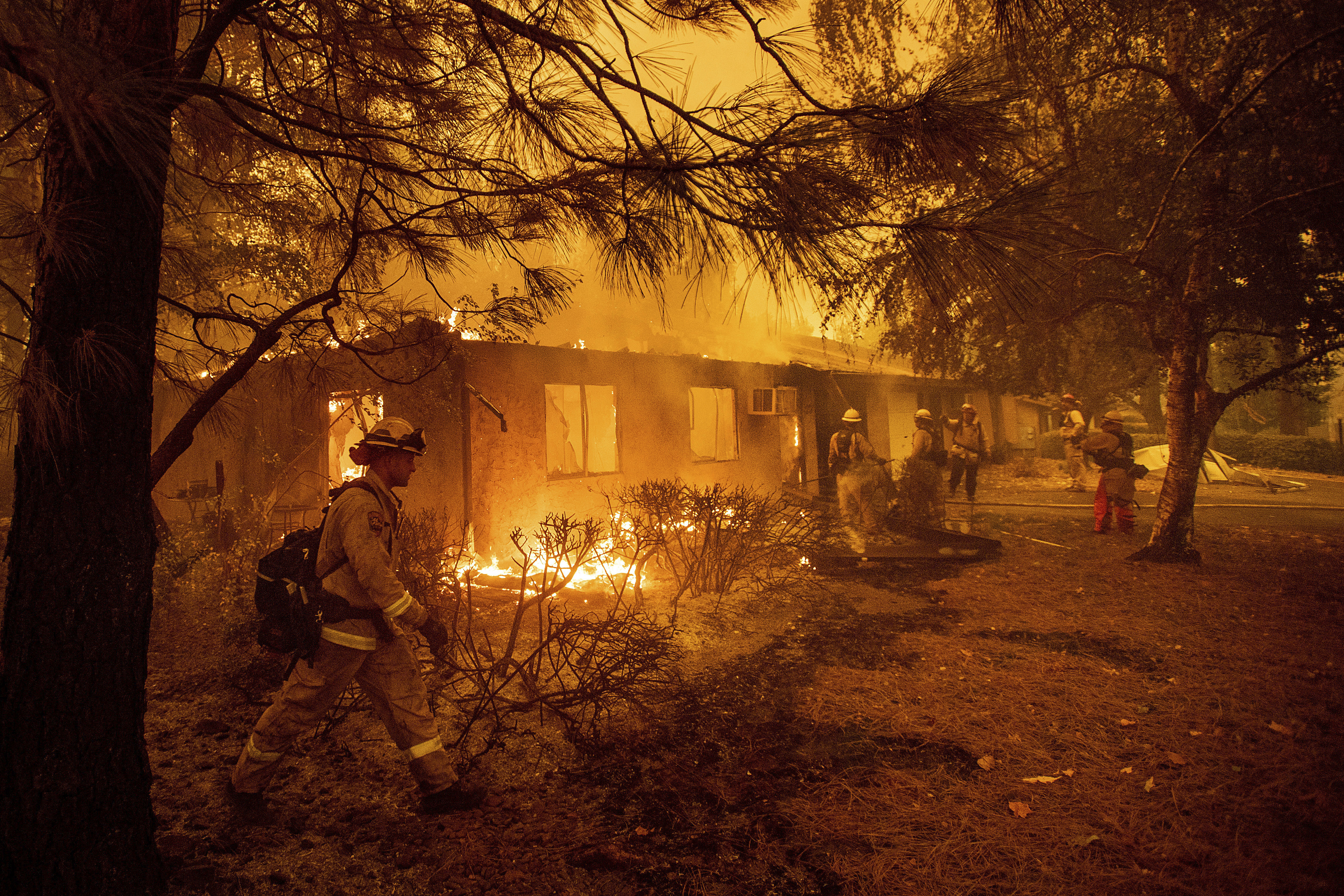 FILE - Firefighters work to keep flames from spreading through the Shadowbrook apartment complex as a wildfire burns through Paradise, Calif., on Nov. 9, 2018. (AP Photo/Noah Berger, File)