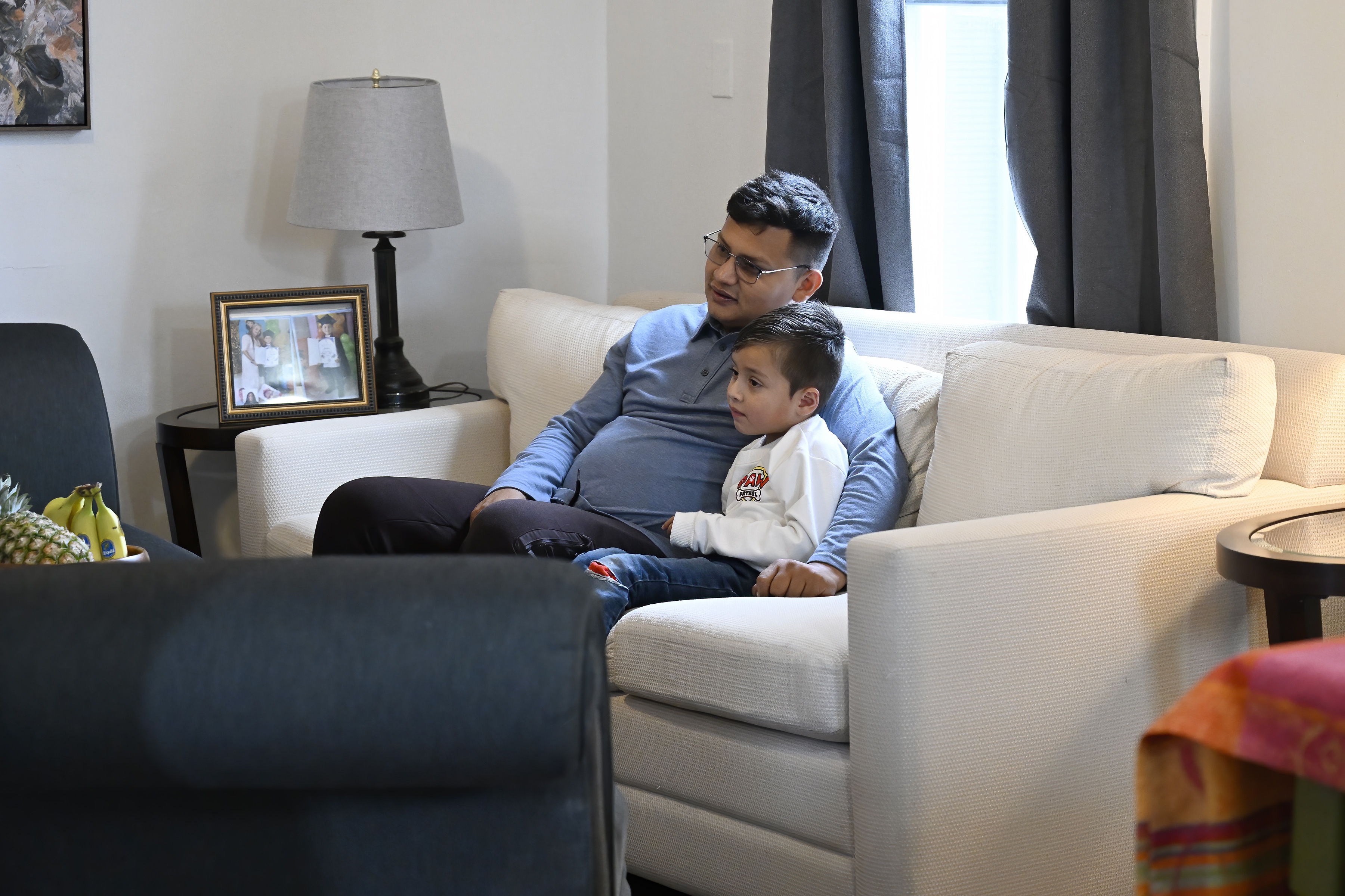 In this Jan. 3, 2025 photo, Rogers Lopez watches television with his son Jesus Lopez in their apartment in New Milford, Conn. (AP Photo/Jessica Hill)