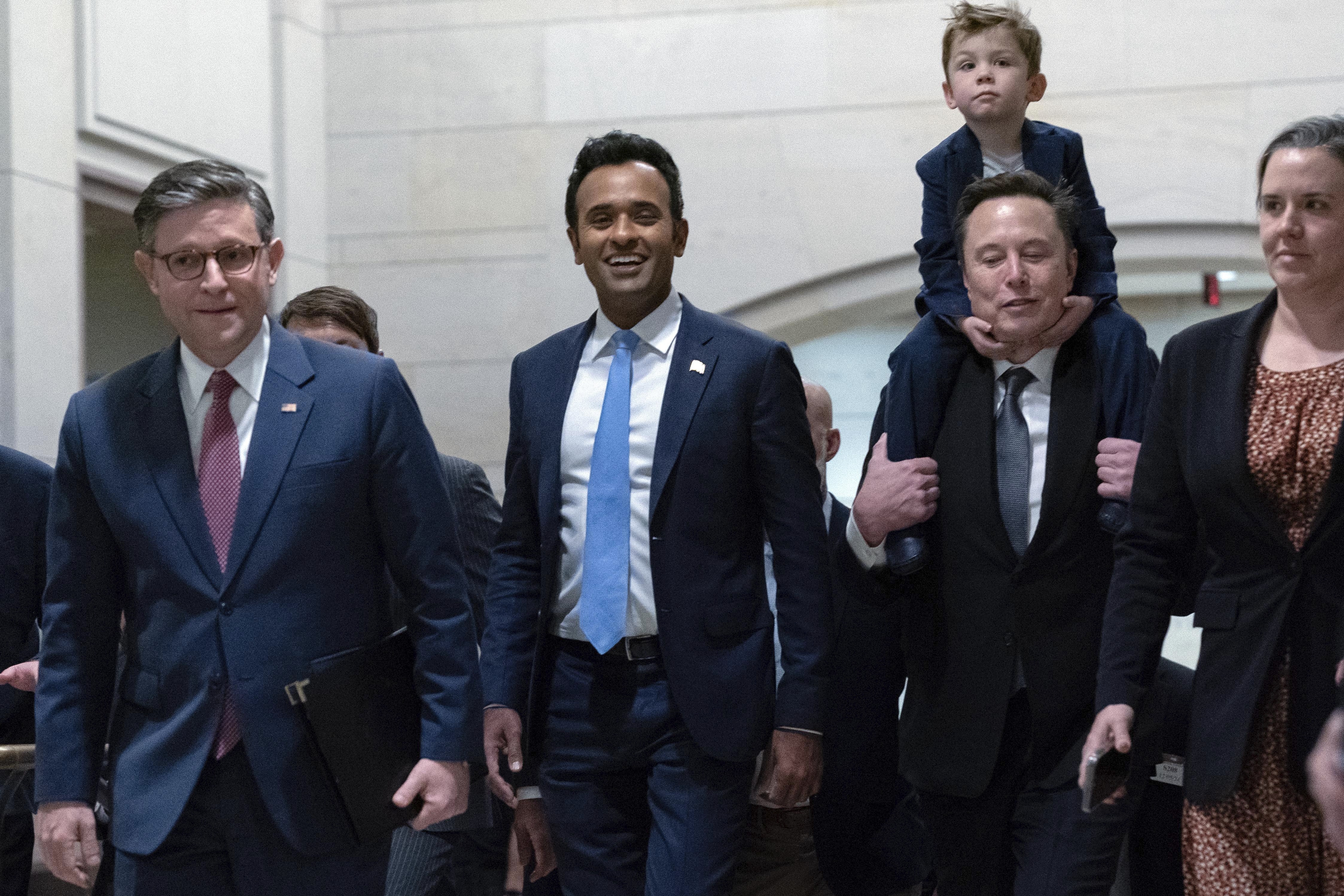 FILE - Speaker of the House Mike Johnson, R-La., from left, walks with Vivek Ramaswamy and Elon Musk, who is carrying his son X Æ A-Xii, as they walk to a meeting to discuss President-elect Donald Trump's planned Department of Government Efficiency, on Capitol Hill in Washington, Dec. 5, 2024. (AP Photo/Jose Luis Magana, File)