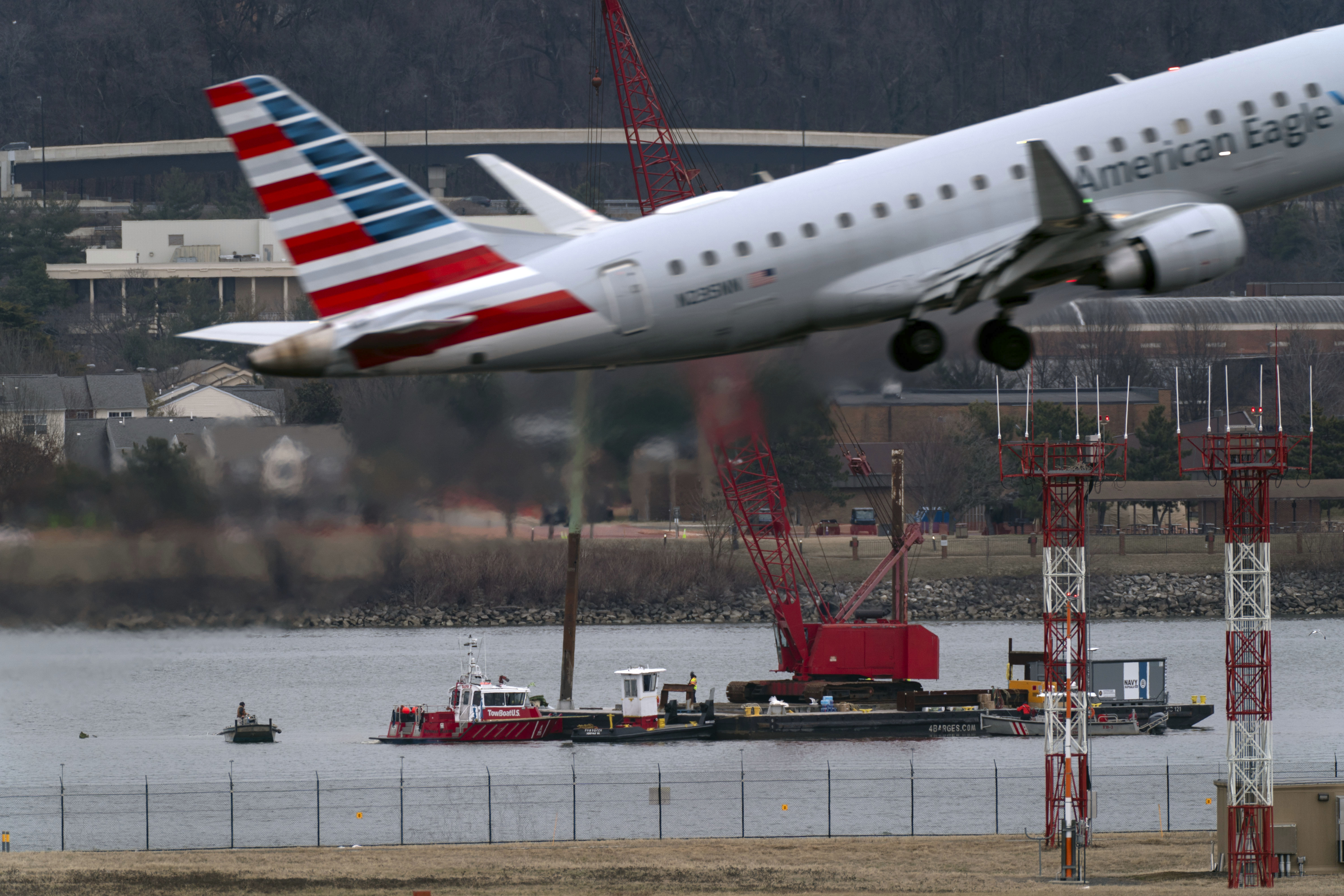 An American Eagle jet passes as rescue and salvage crews work near the wreckage of an American Airlines jet in the Potomac River from Ronald Reagan Washington National Airport, Sunday, Feb. 2, 2025, in Arlington, Va. (AP Photo/Jose Luis Magana)