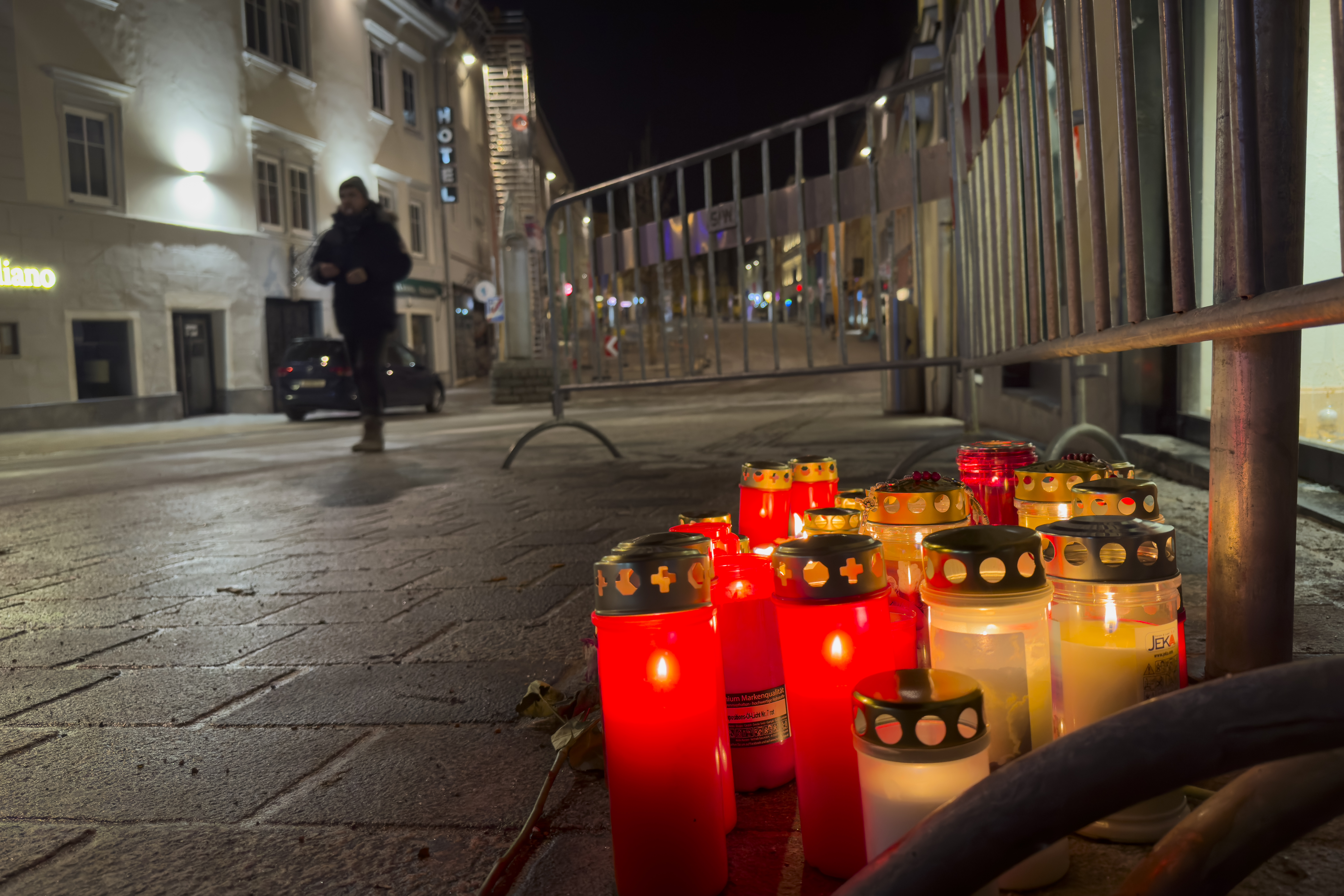 A pedestrian walk past candles at the site of a stabbing attack in Villach, Austria, Sunday, Feb. 16, 2025. (AP Photo/Darko Bandic)