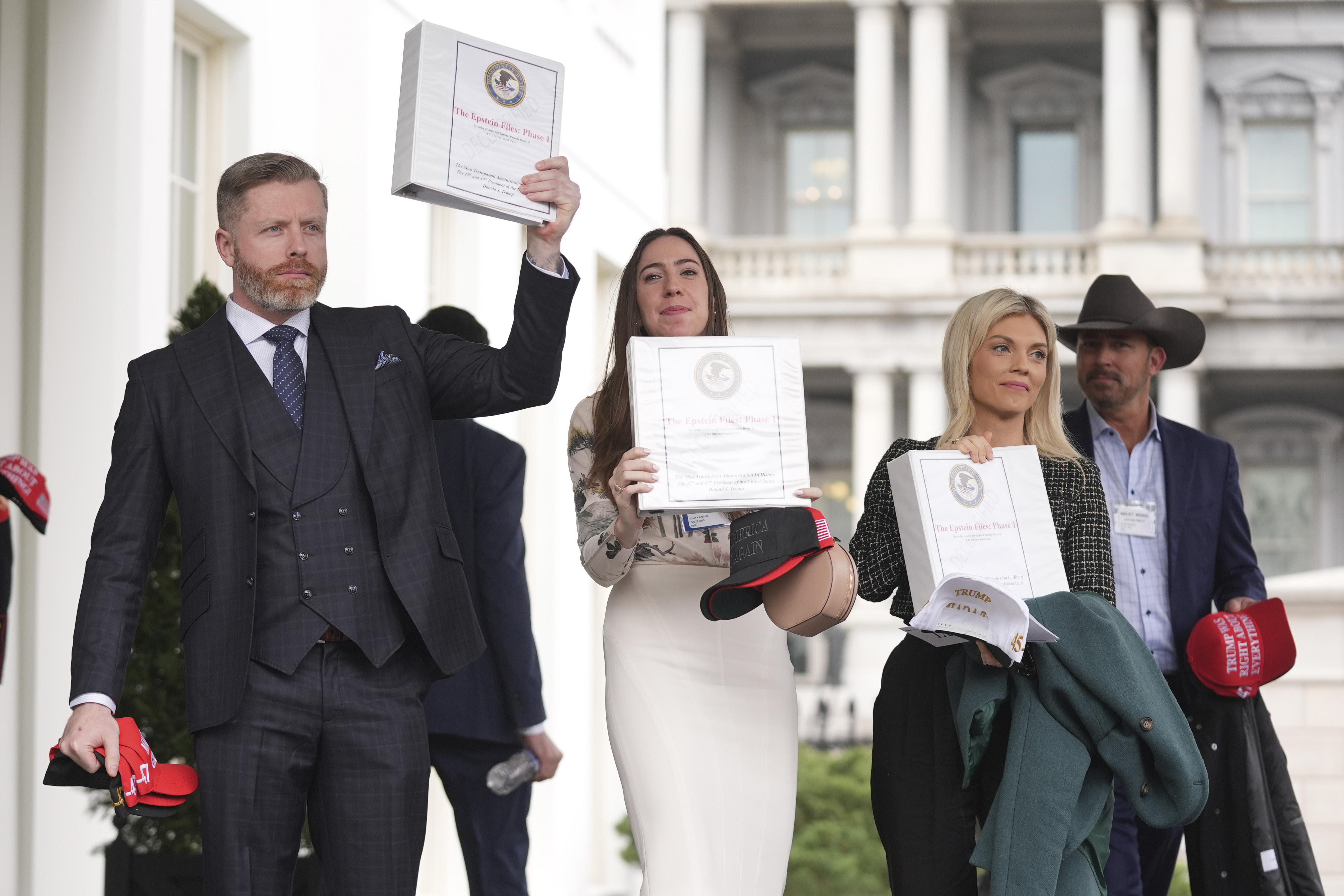 Conservative political commentator Rogan O'Handley, also known as DC Draino, from left, social media content creator Chaya Raichik and conservative political commentator Liz Wheeler hold up binders with a cover titled "The Epstein Files: Phase 1," with Jack Posobiec at the White House, Thursday, Feb. 27, 2025, in Washington. (AP Photo/Evan Vucci)