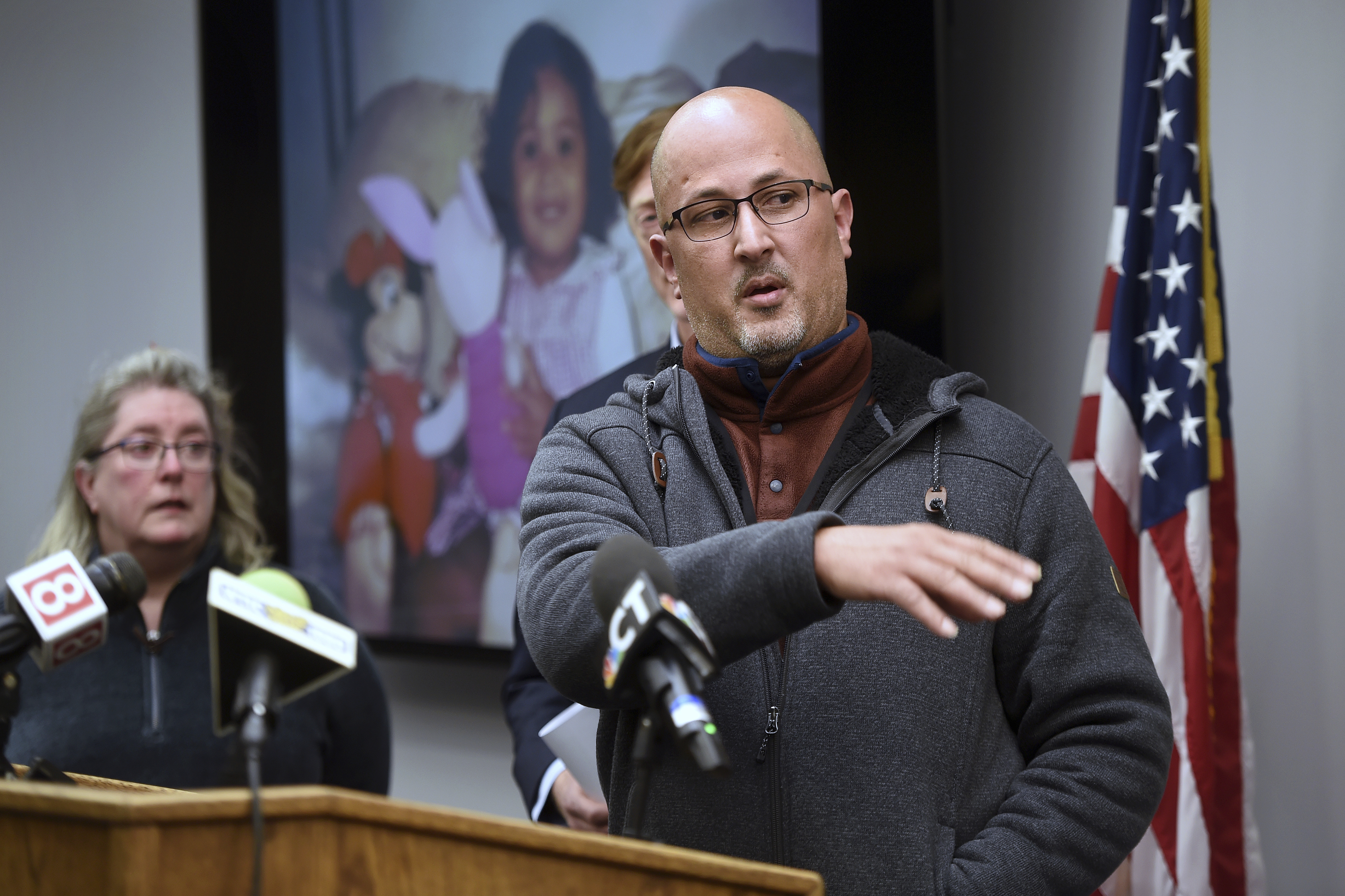 Carlos Reyes-Couvertier speaks at a news conference at the New Haven Police Department on Wednesday, March 12, 2025 concerning the solving of the cold case of the parental abduction in 1999 of his daughter, Andrea Reyes. Behind him is a photo of his daughter as a child. (Arnold Gold/ Hearst Connecticut Media via AP)