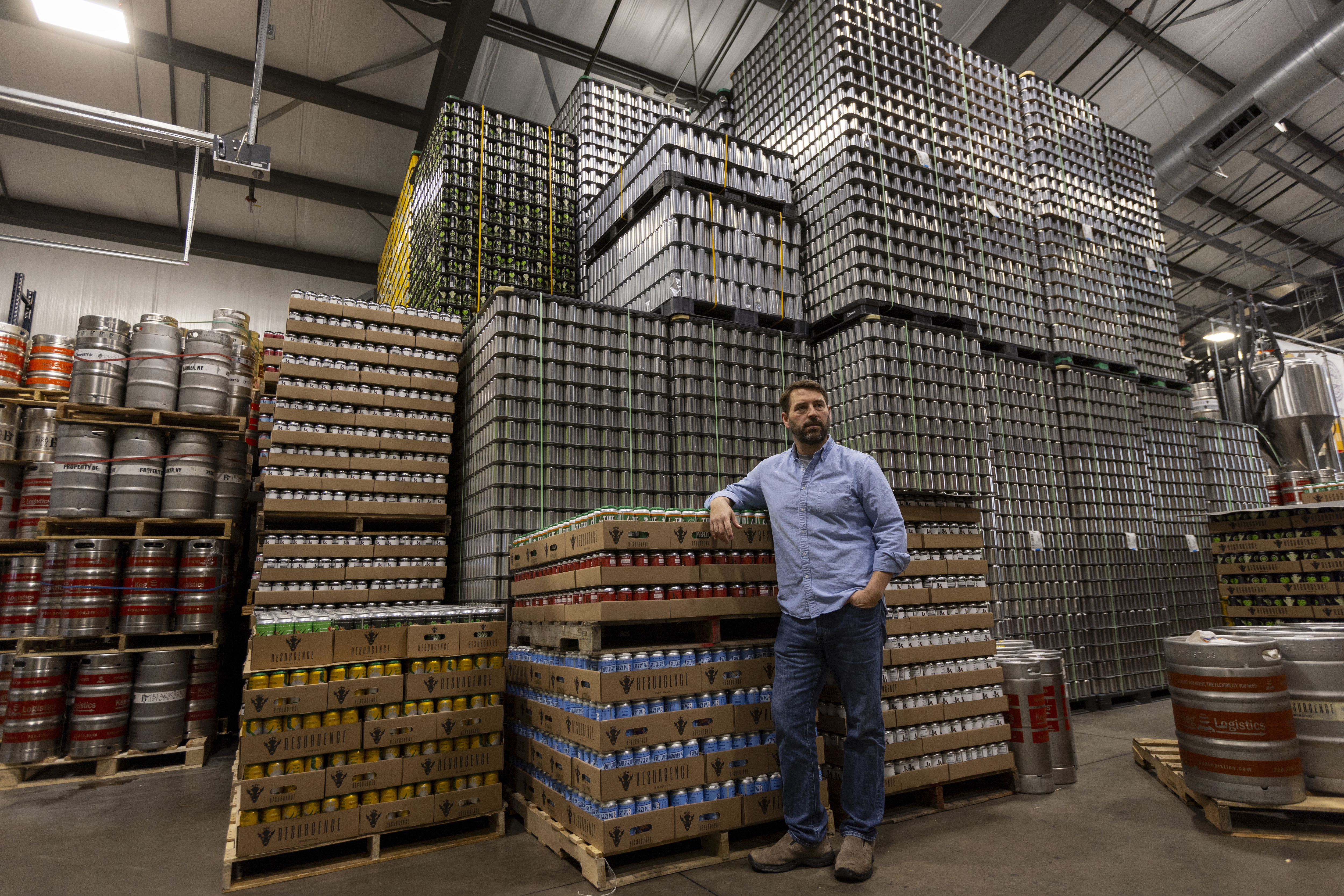 Jeff Ware, president of Resurgence Brewing Company, poses for a portrait near a stockpile of aluminum cans, which are sourced from Canada, Thursday, Feb. 27, 2025, in Buffalo, N.Y. (AP Photo/Lauren Petracca)